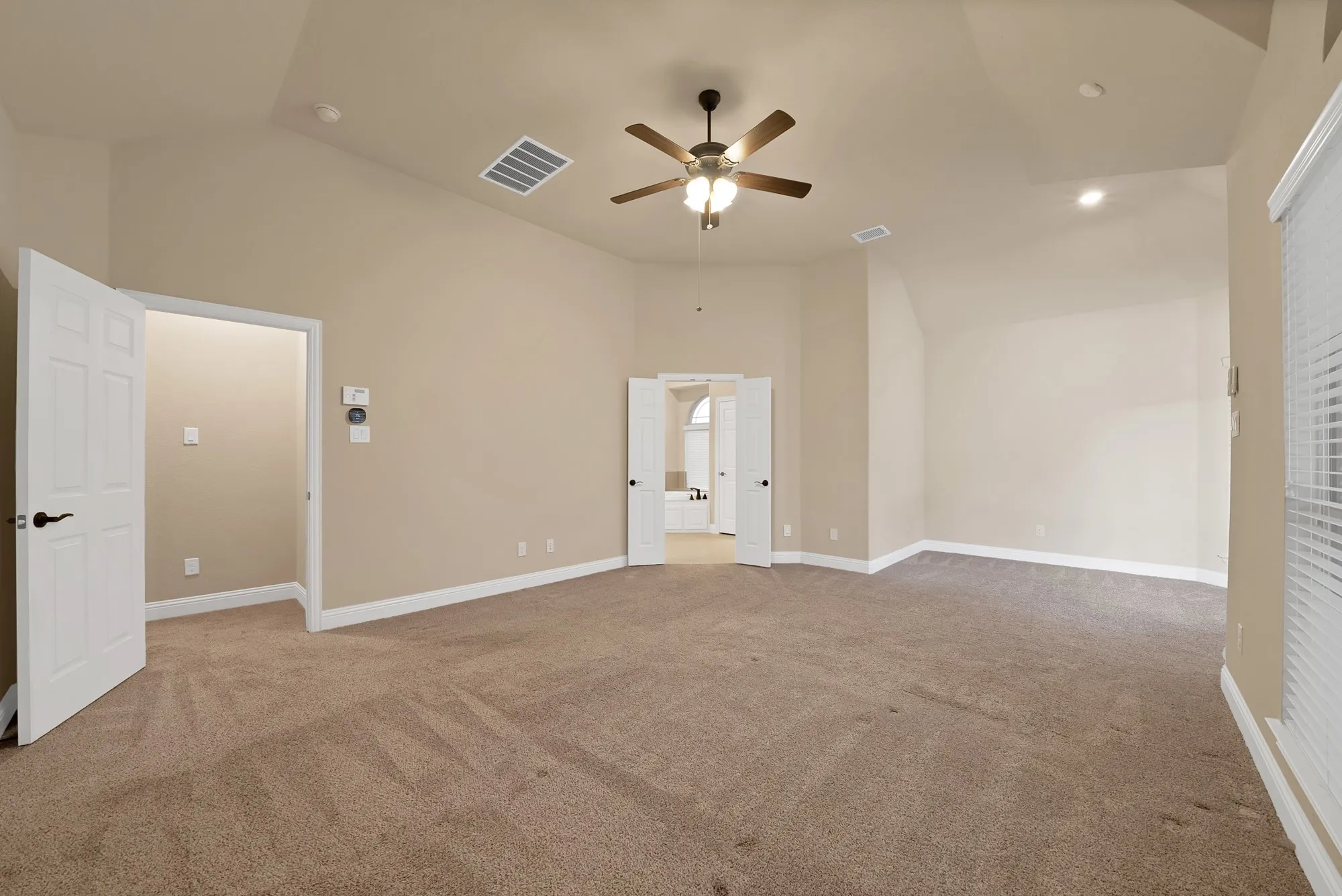 Spacious room with vaulted ceiling, plush carpet flooring, ceiling fan, recessed lighting, and white paneled doors