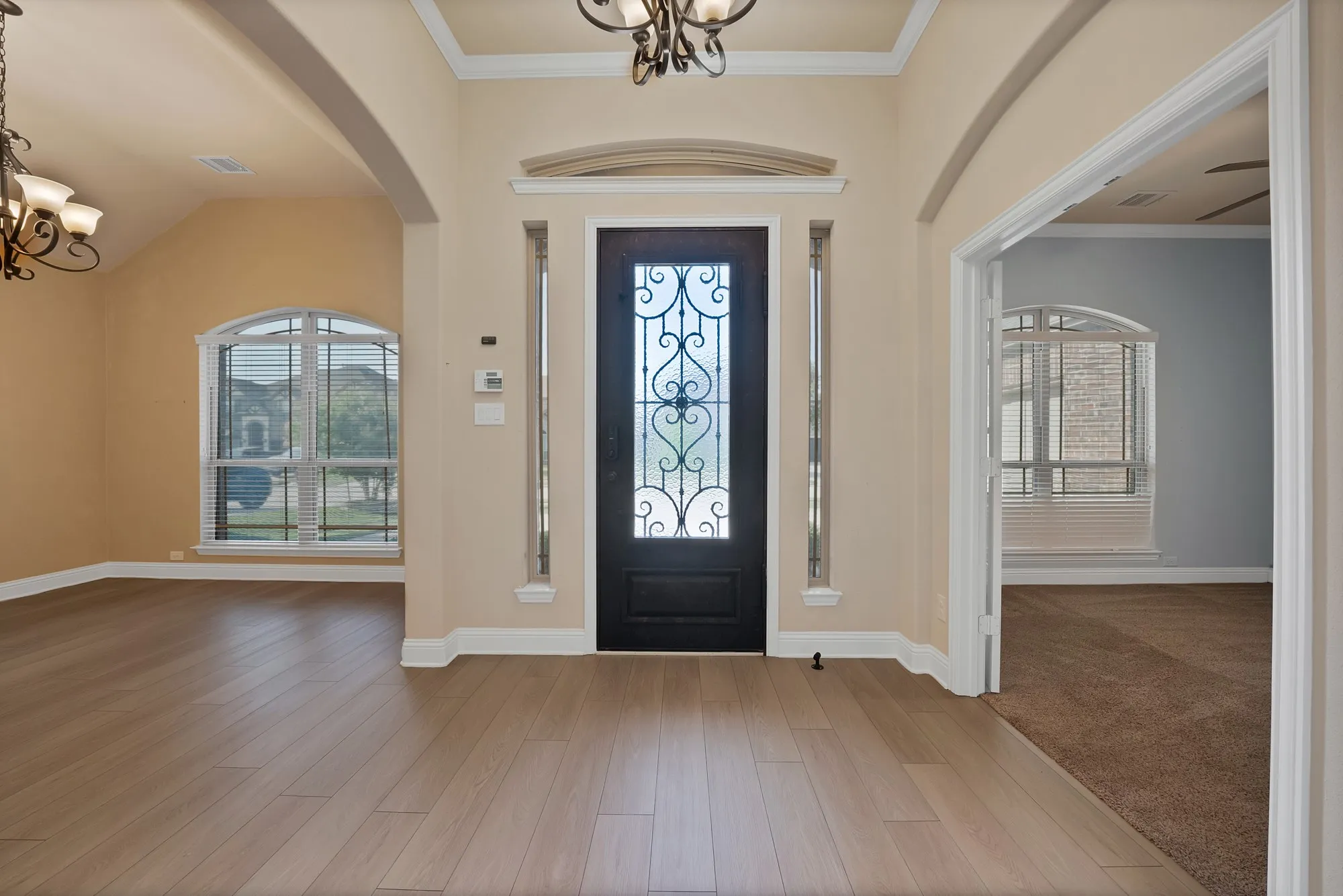 Entryway featuring a decorative glass front door, side panel windows, arched doorways, wood-finish flooring, and crown molding