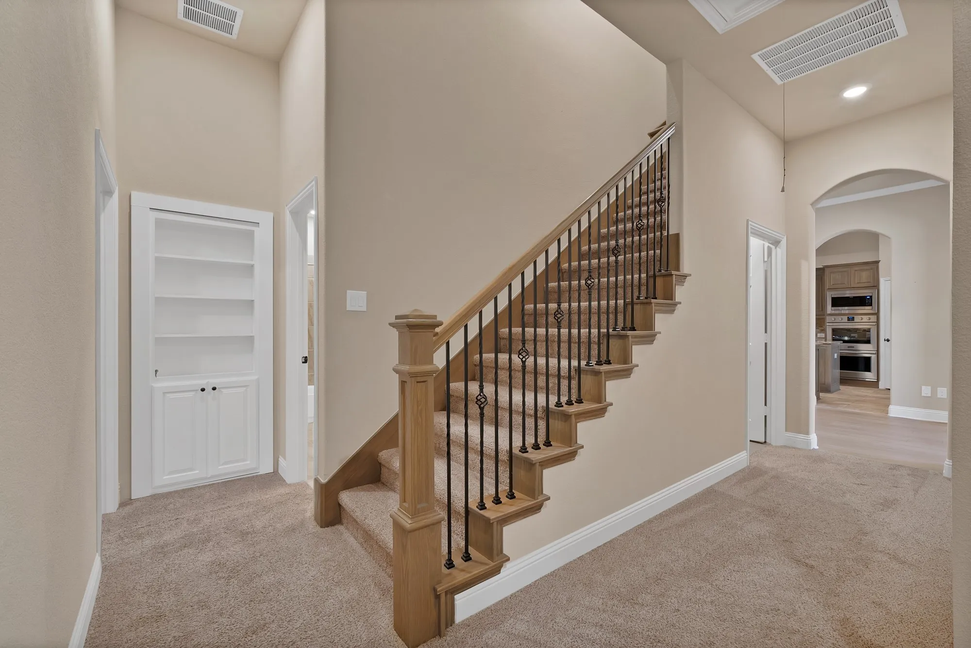 Staircase with wood newel posts, wood handrail, and wrought iron balusters