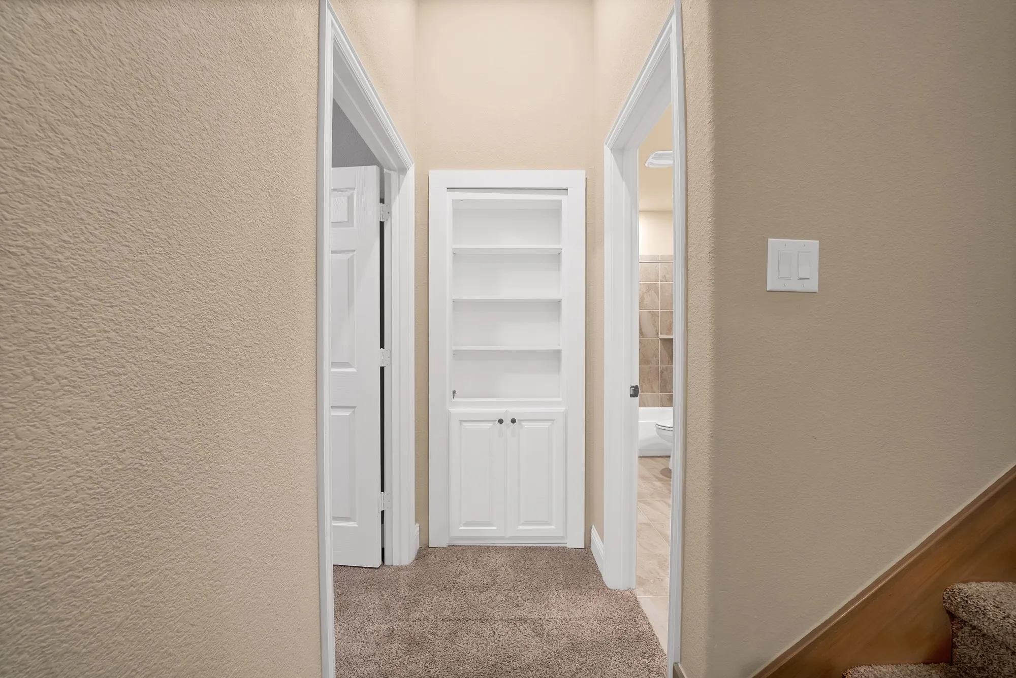 Hallway featuring carpet flooring, built-in shelving with cabinet storage, and light-toned walls