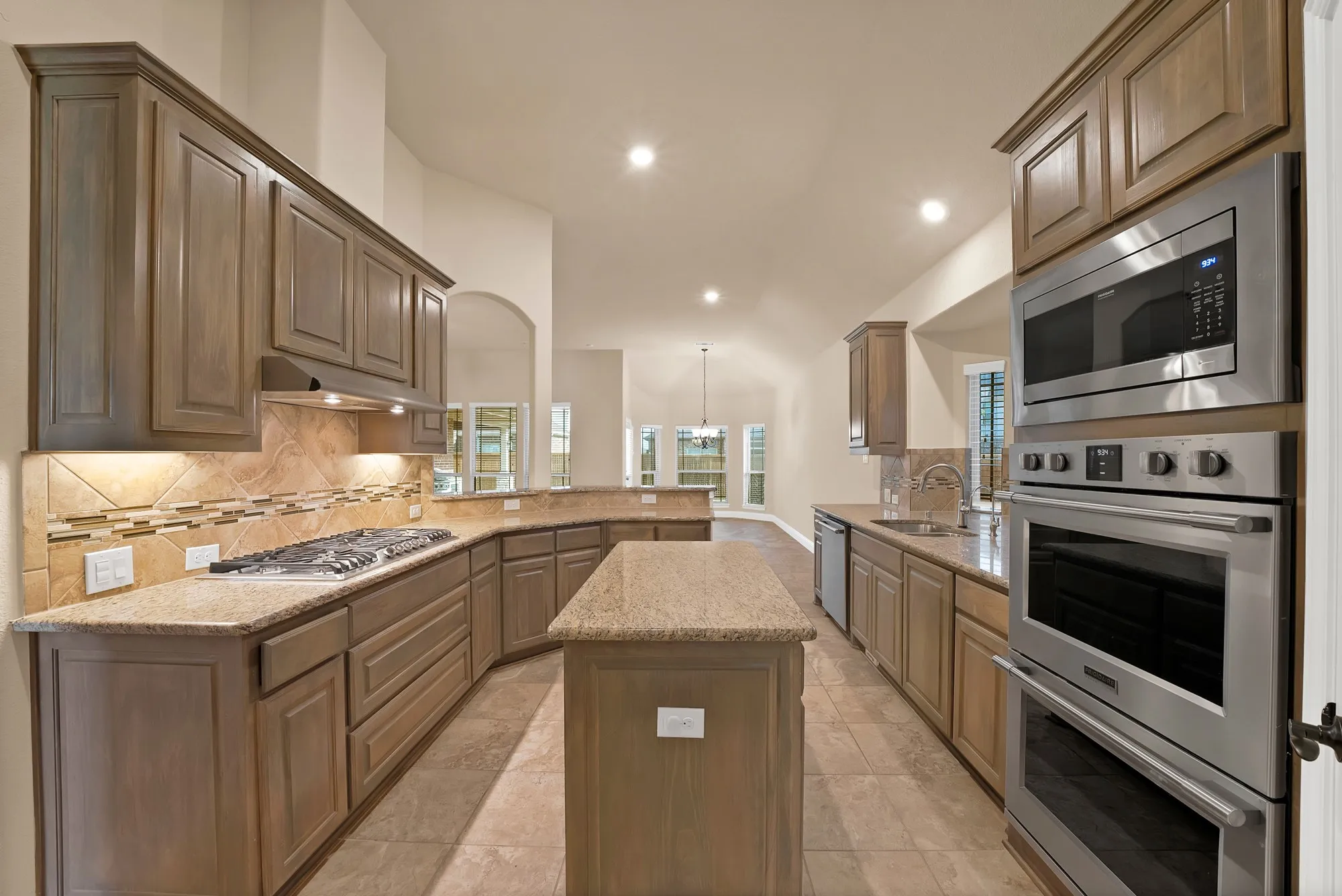 Kitchen featuring a gas cooktop, built-in microwave, double oven, stone countertops, and tile flooring