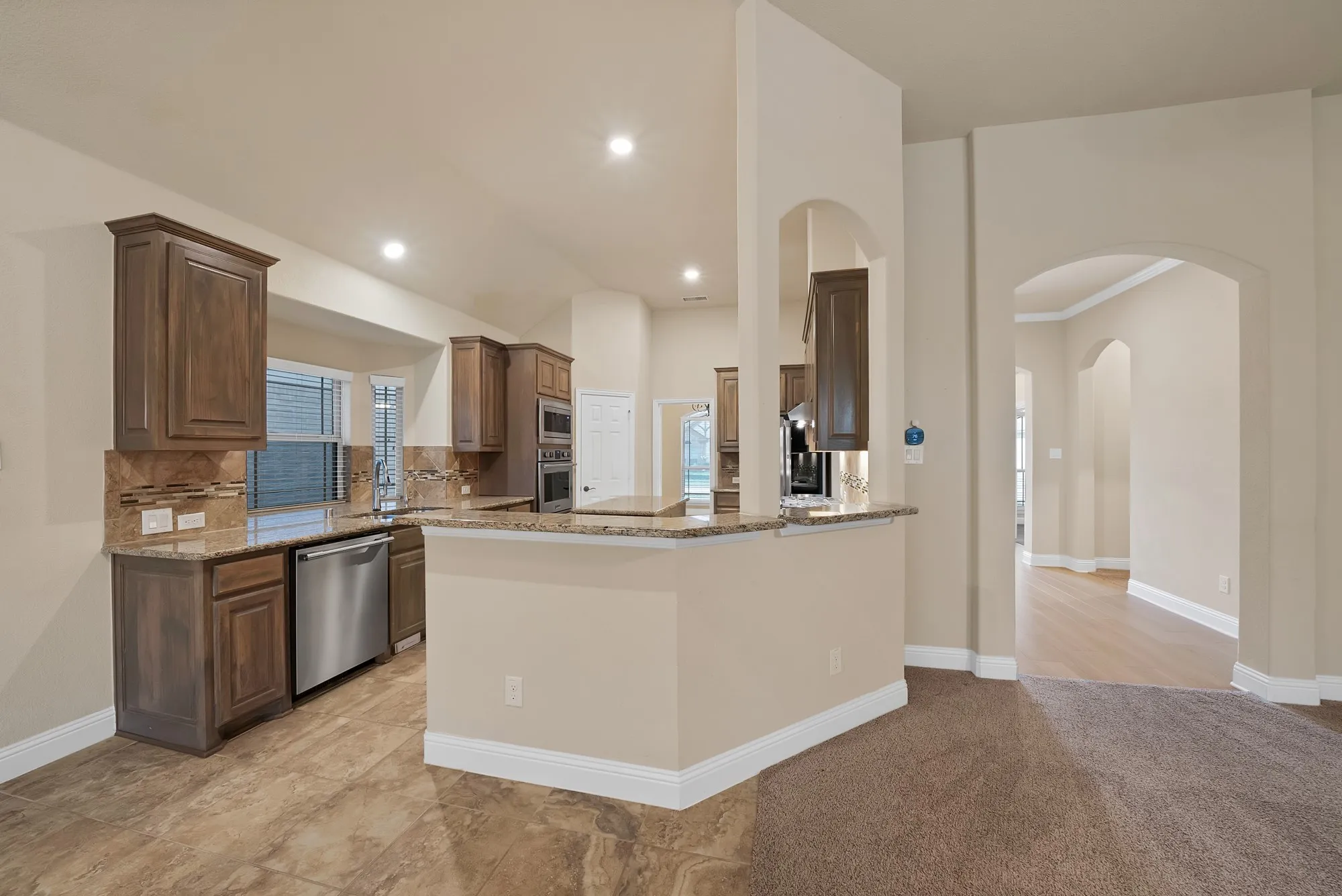 Kitchen featuring wood cabinetry, stainless steel appliances, granite countertops, and a tile backsplash