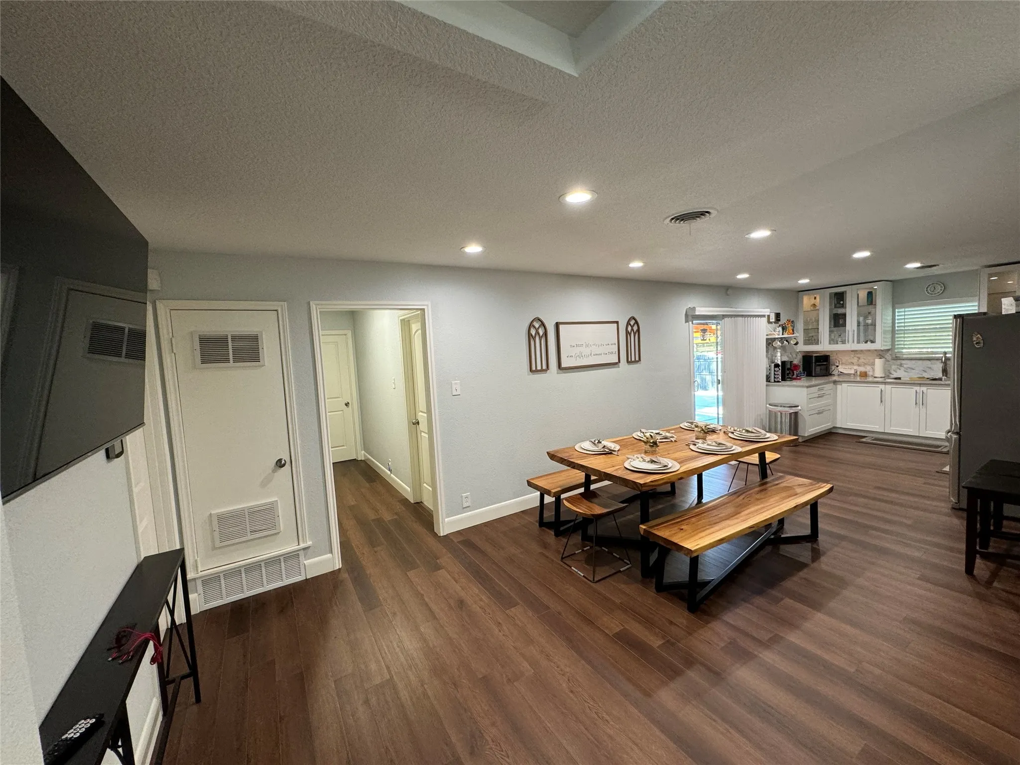 Recessed lighting, wood-finish flooring, white cabinetry, frosted glass cabinet doors, and a sliding glass door