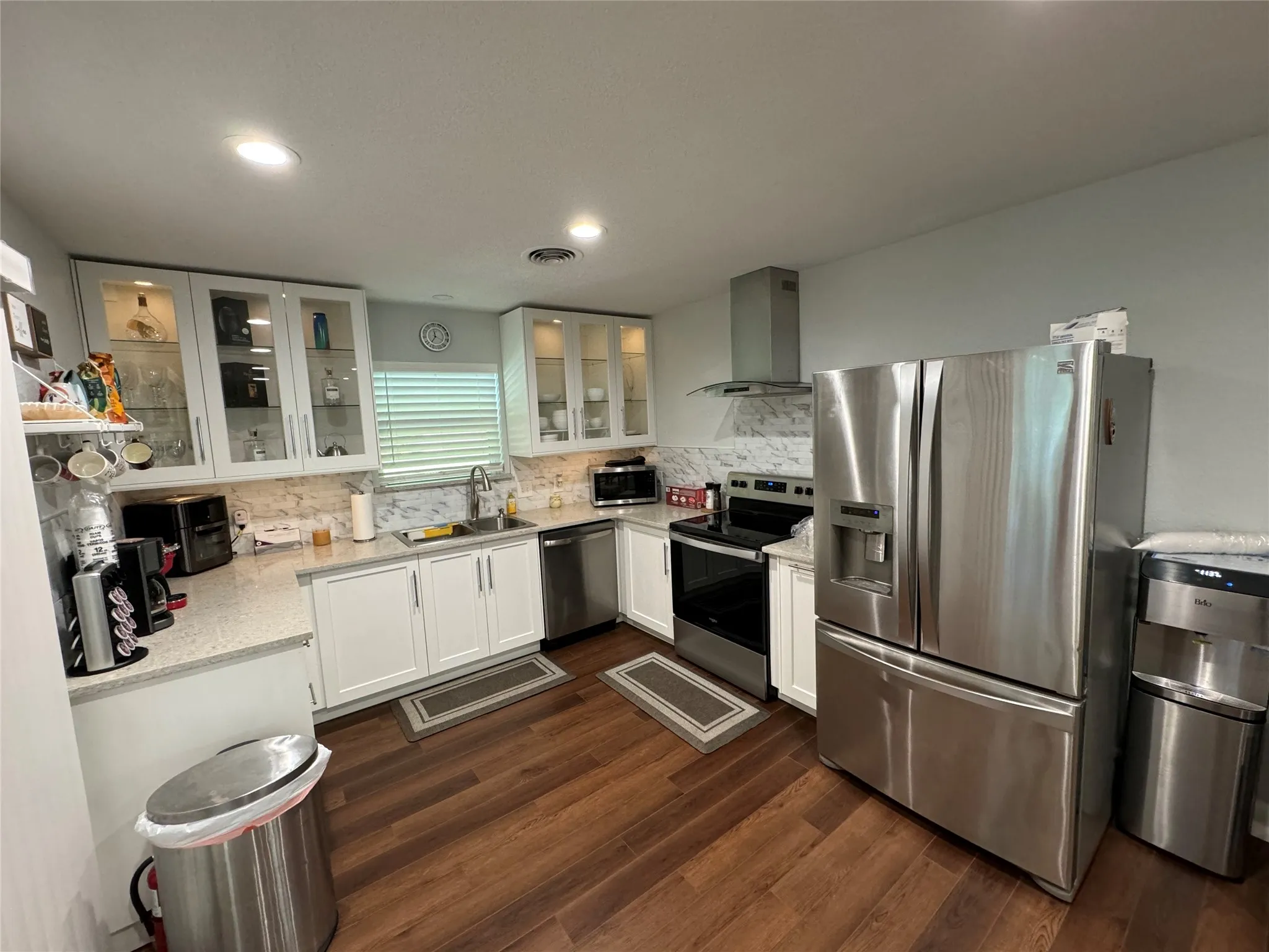 Wood-finish flooring with white cabinetry, stainless steel appliances, and recessed lighting