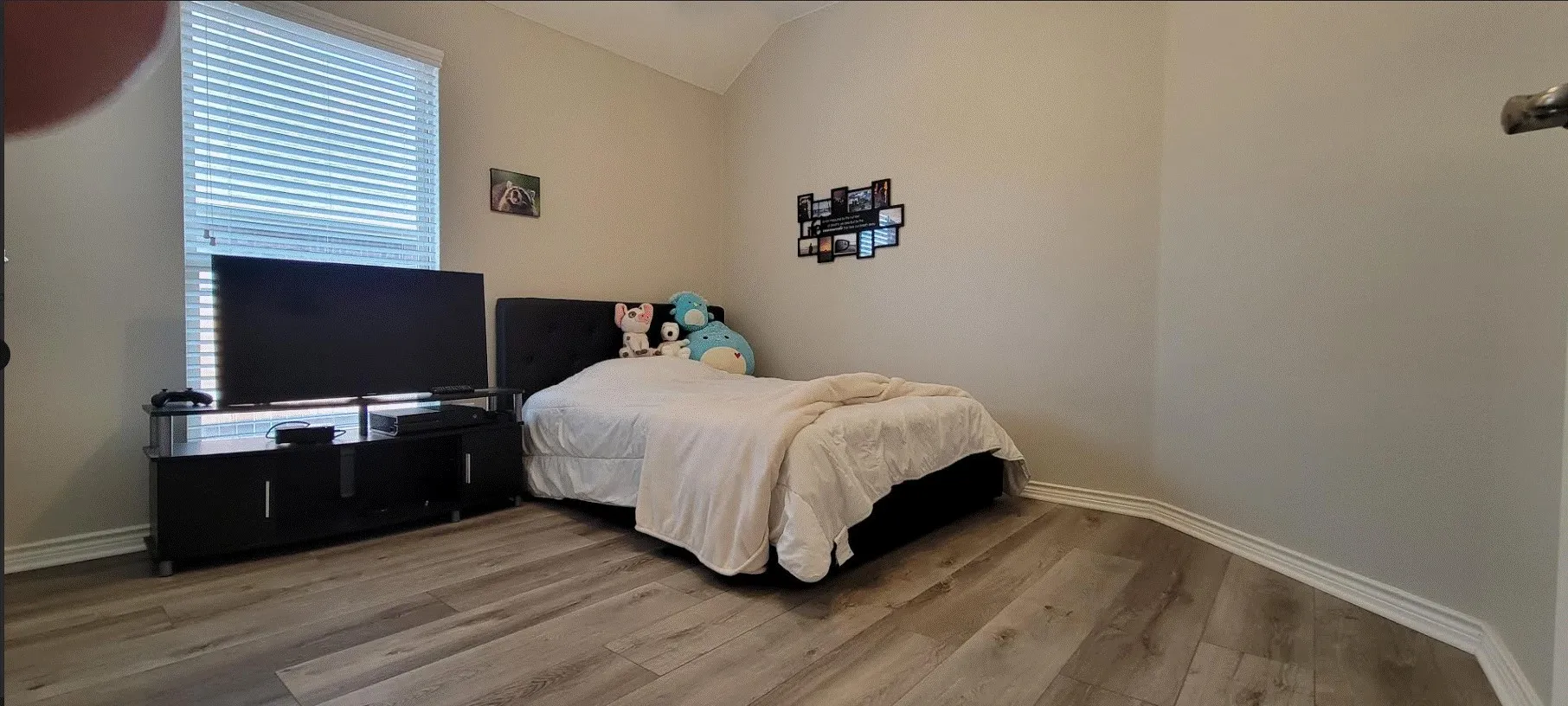 Vaulted ceiling with a window, wood-finish flooring, and neutral wall tones