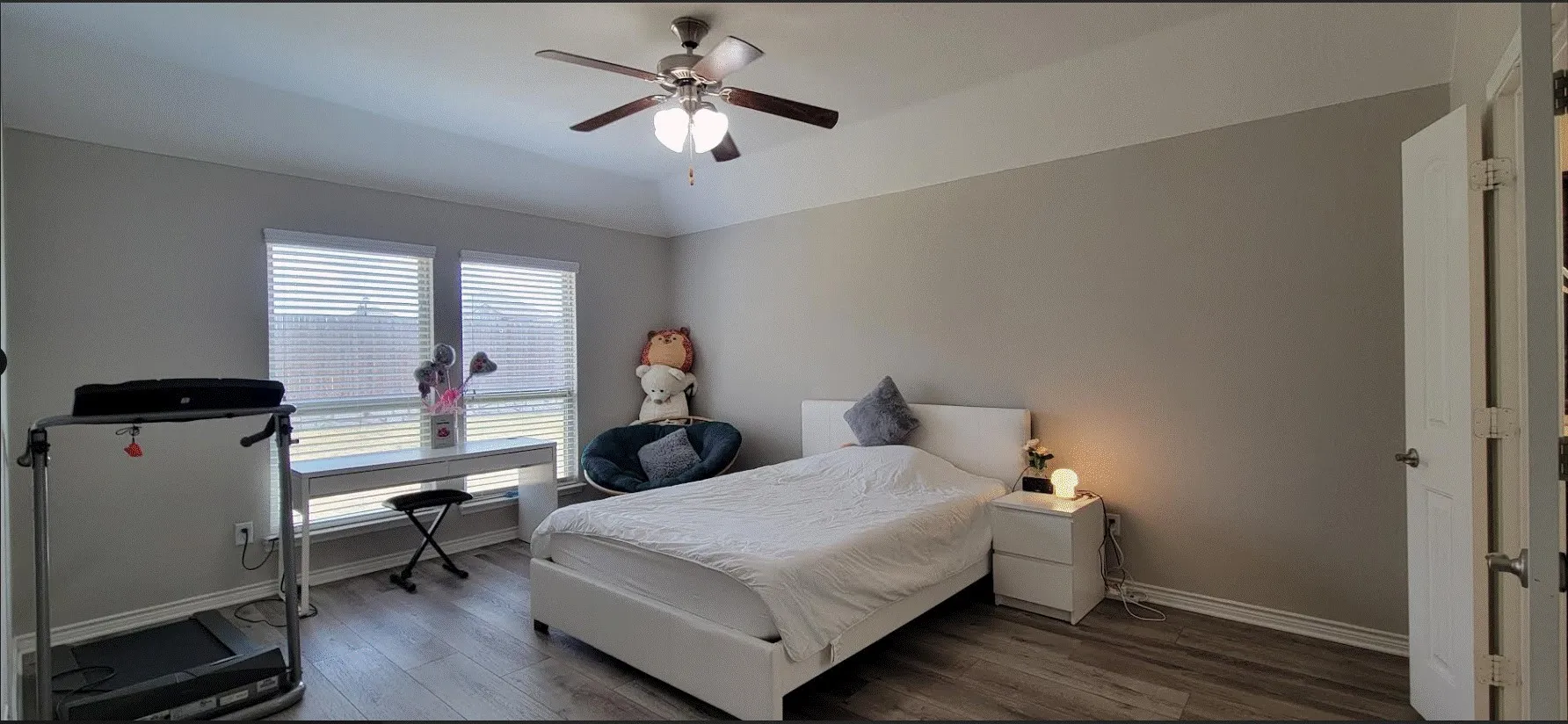 Tray ceiling with a ceiling fan, two windows with blinds, wood-finish flooring, and light-toned wall paint