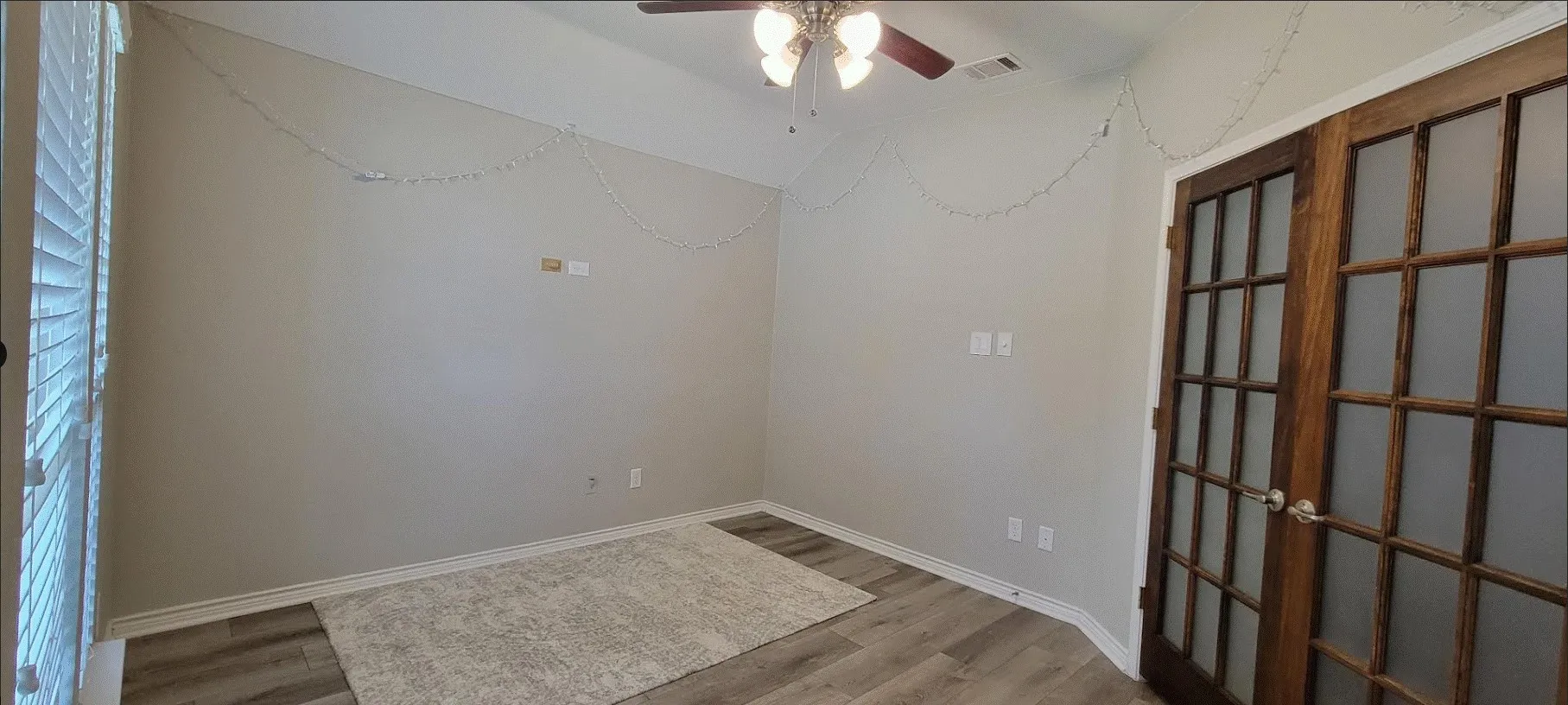 Wood-finish flooring, ceiling fan with integrated lighting, wood frame French doors with frosted glass, and white trim