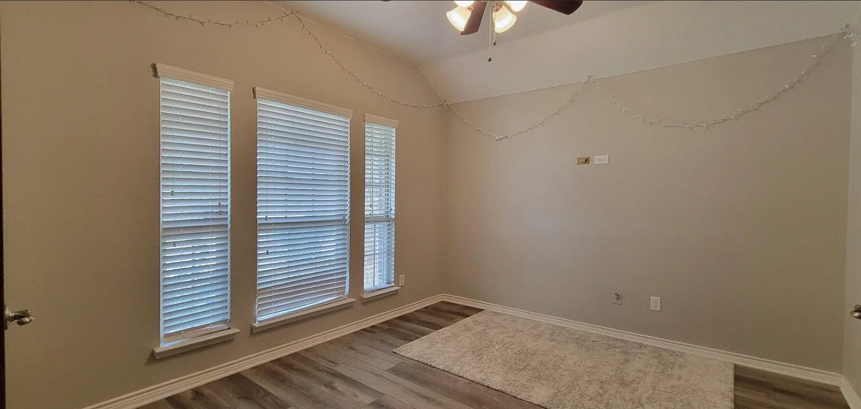 Bright corner room flooded with natural light through three large windows fitted with plantation shutters