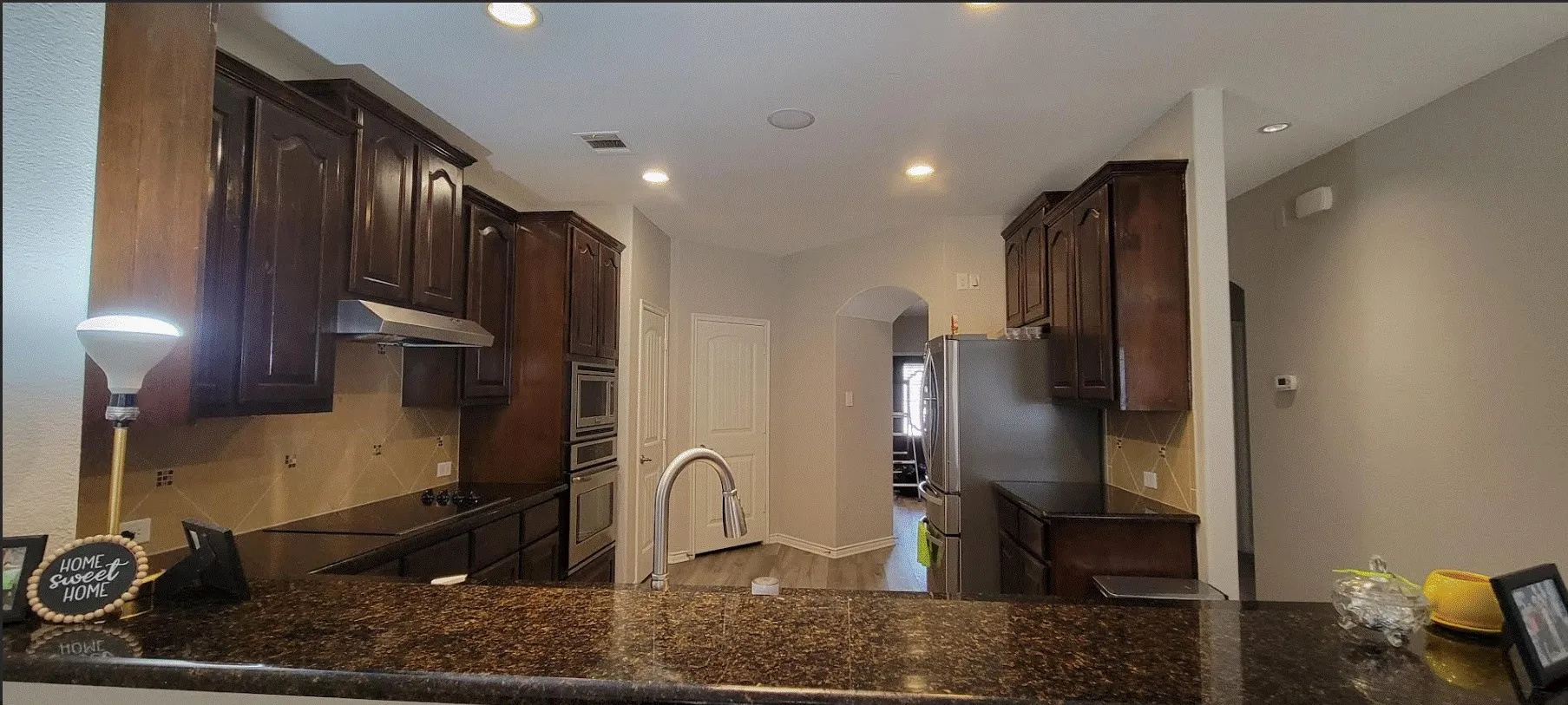 Kitchen featuring dark wood cabinetry, stainless steel appliances, a tile backsplash, and recessed lighting