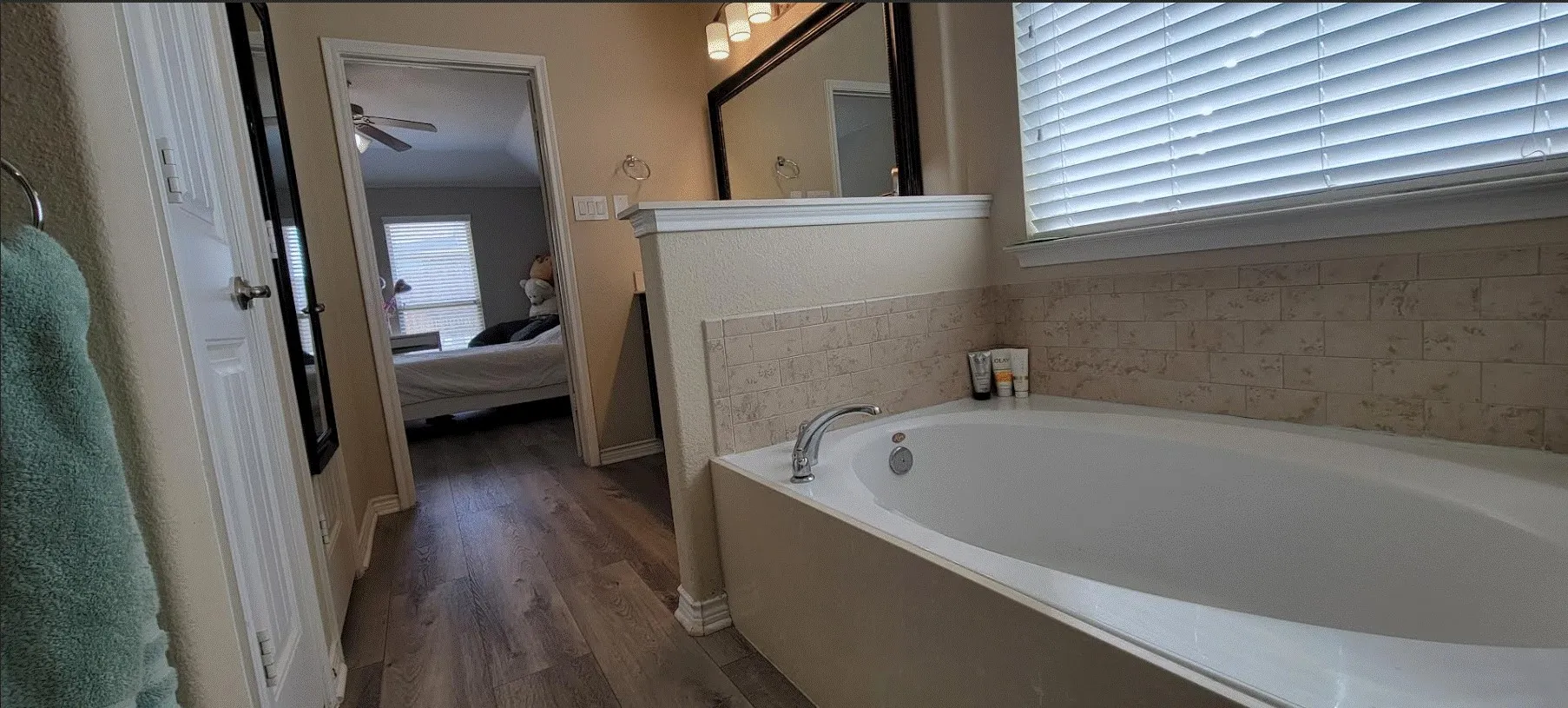 Built-in bathtub with subway tile surround, chrome fixtures, and window with blinds