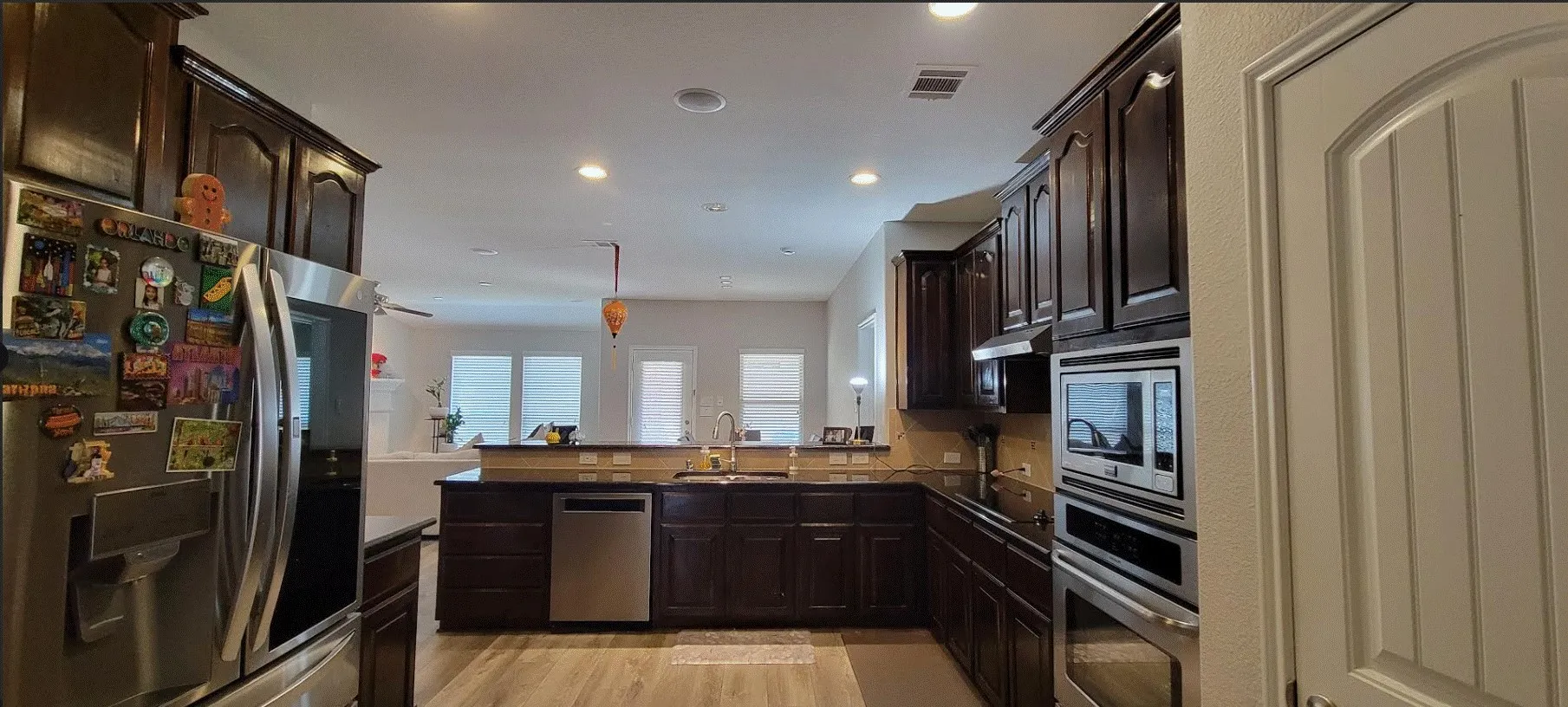 Kitchen featuring dark wood-finish cabinetry, stainless steel appliances, recessed lighting, wood-finish flooring, and a built-in oven and microwave