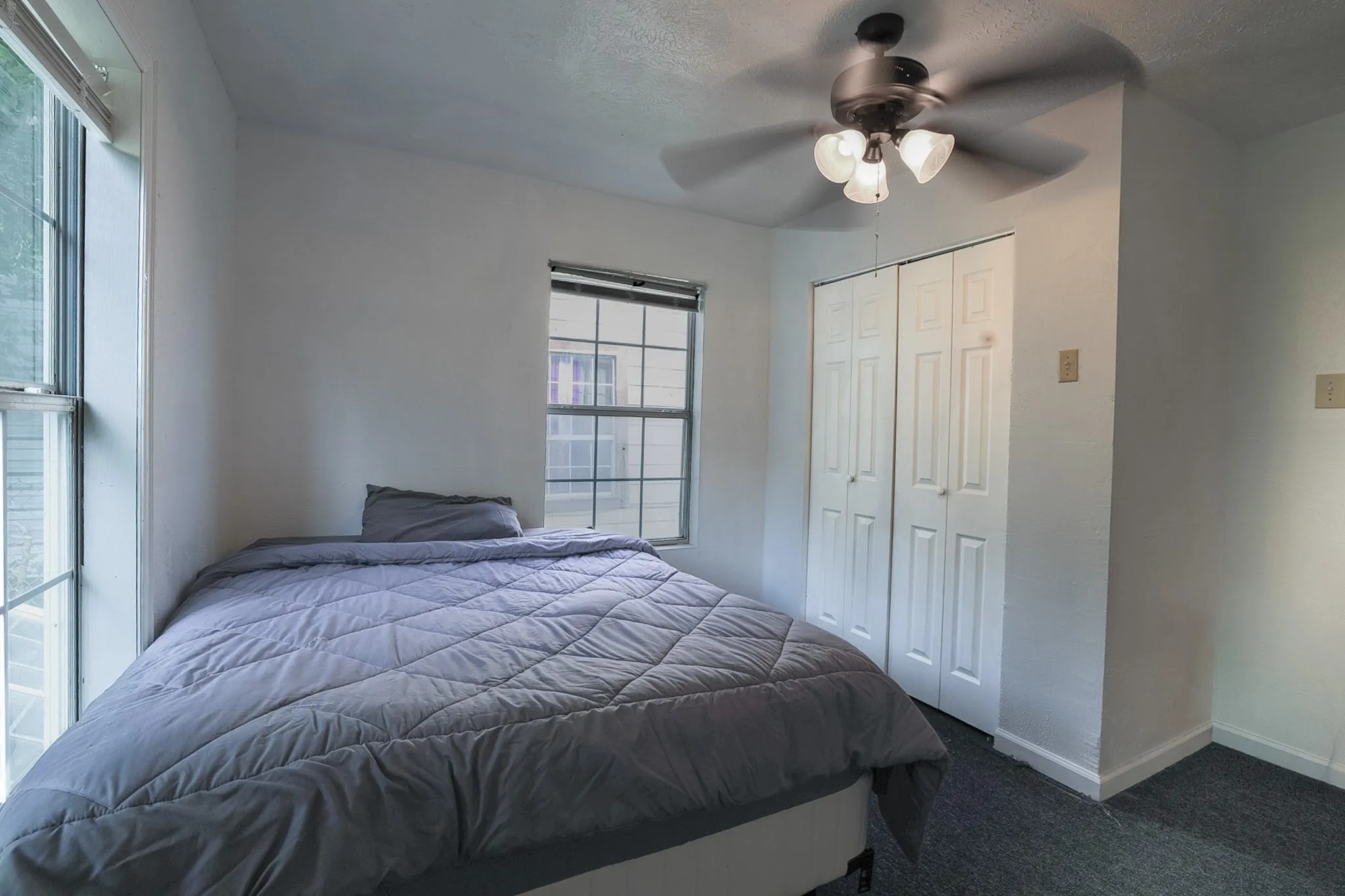 Recessed windows with natural light, textured carpeting, ceiling fan with integrated lighting, and bi-fold closet doors