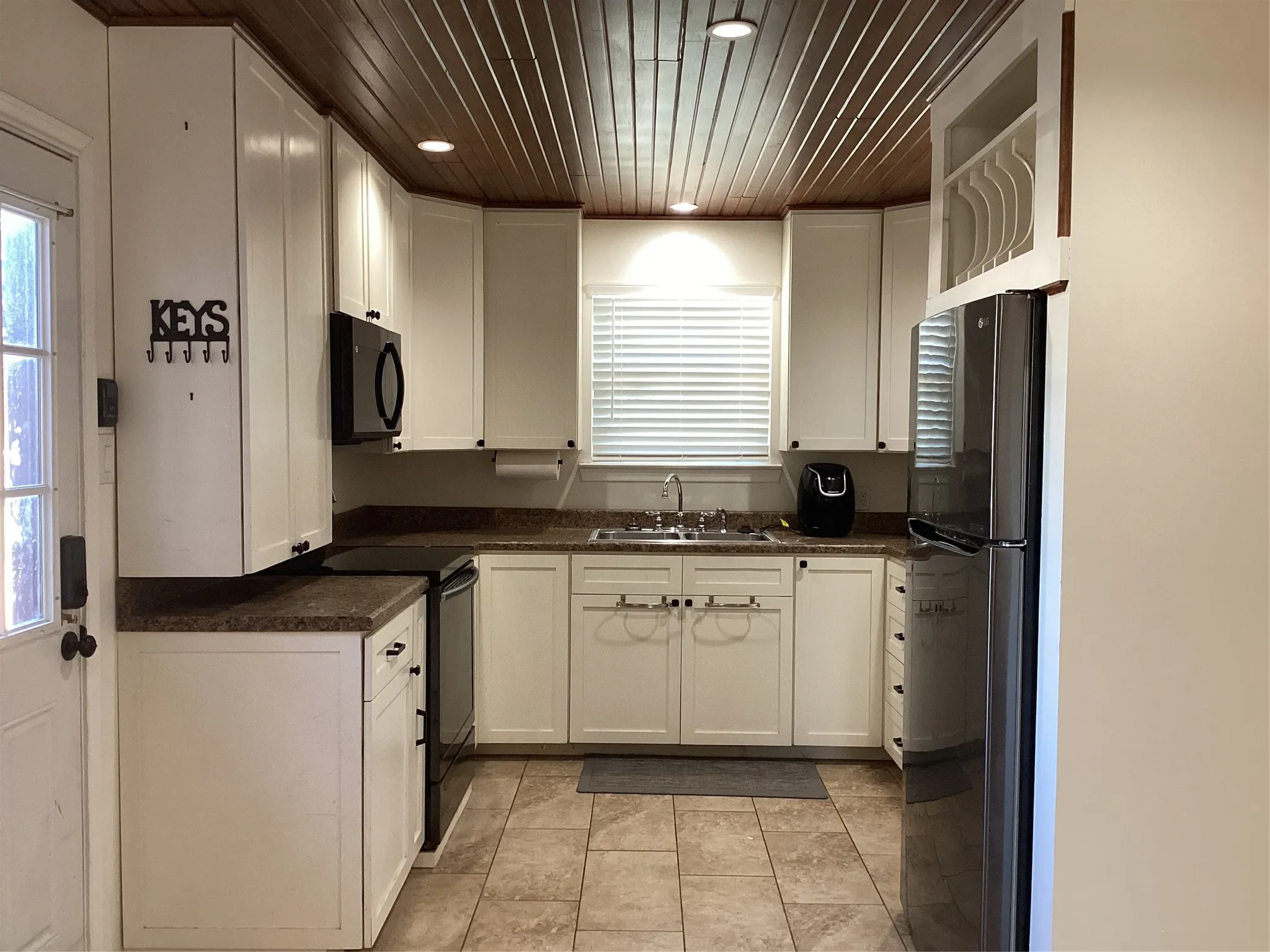 Kitchen featuring a wood-panelled ceiling, recessed lighting, white cabinetry, dark stone-finish countertops, and stainless steel appliances