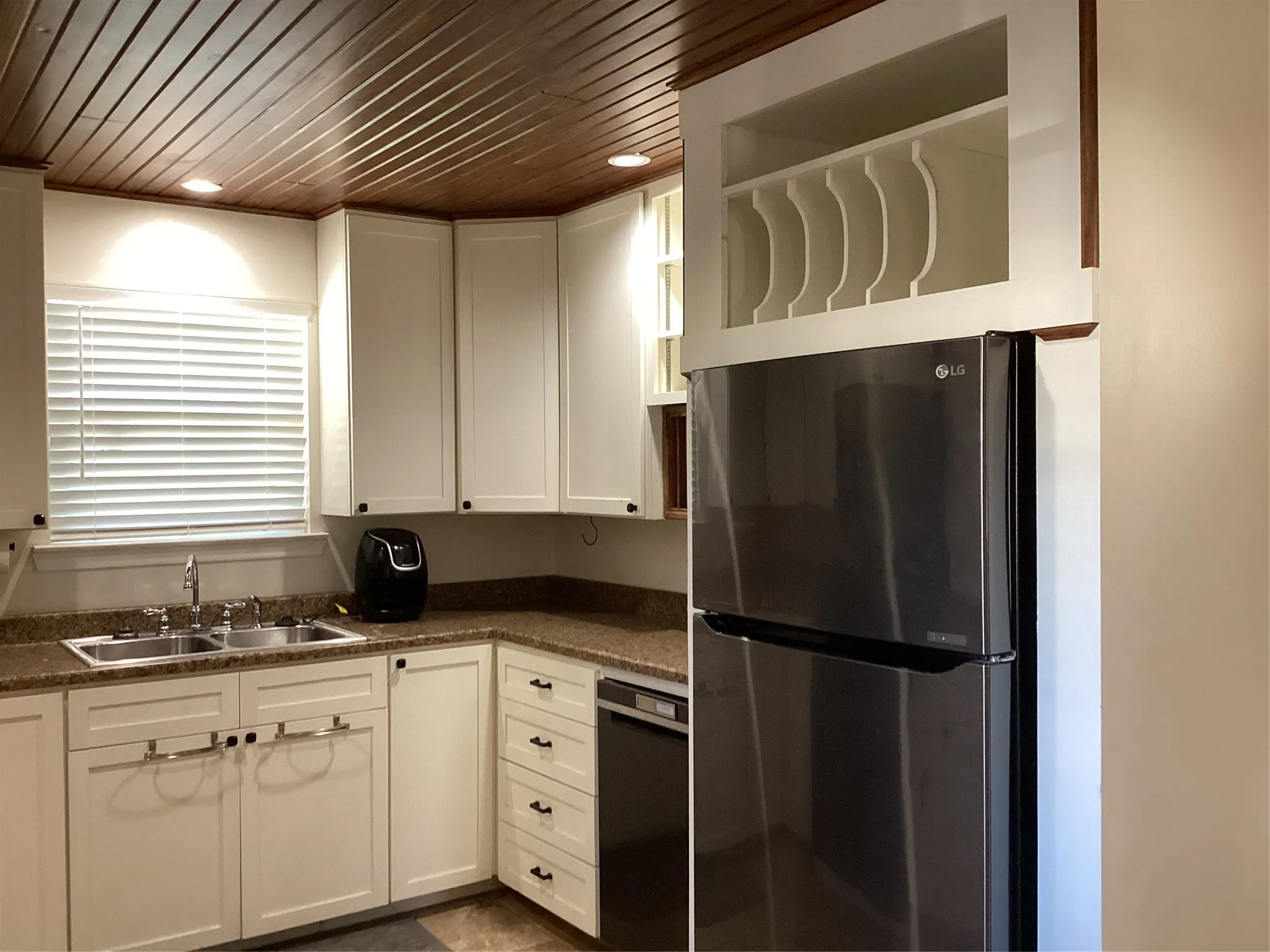 Kitchen featuring a wood-panel ceiling, recessed lighting, white cabinetry, a built-in wine rack, and a stainless steel refrigerator