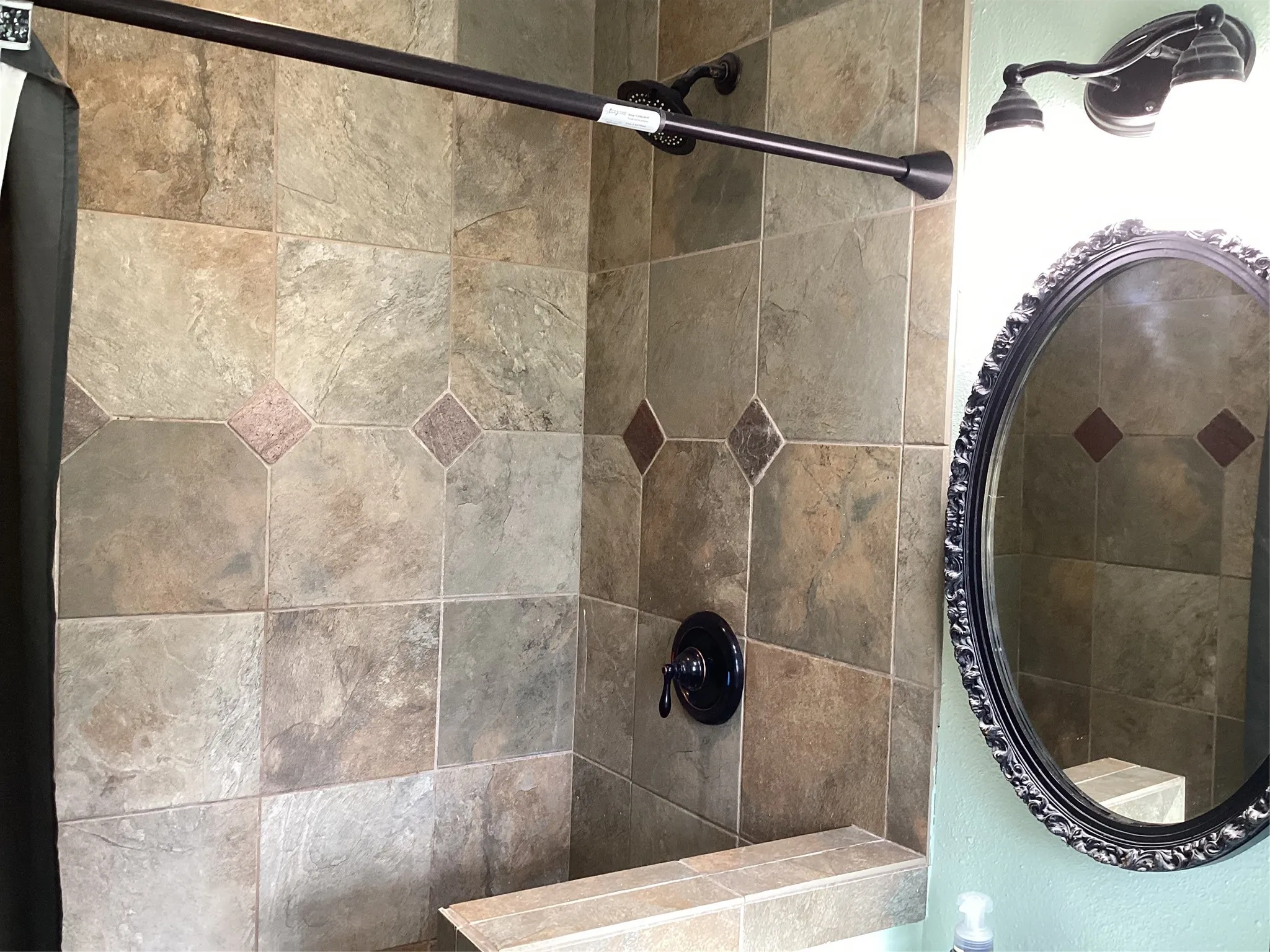 Tiled shower enclosure featuring a built-in bench, dark bronze shower fixture, and coordinated tile accents