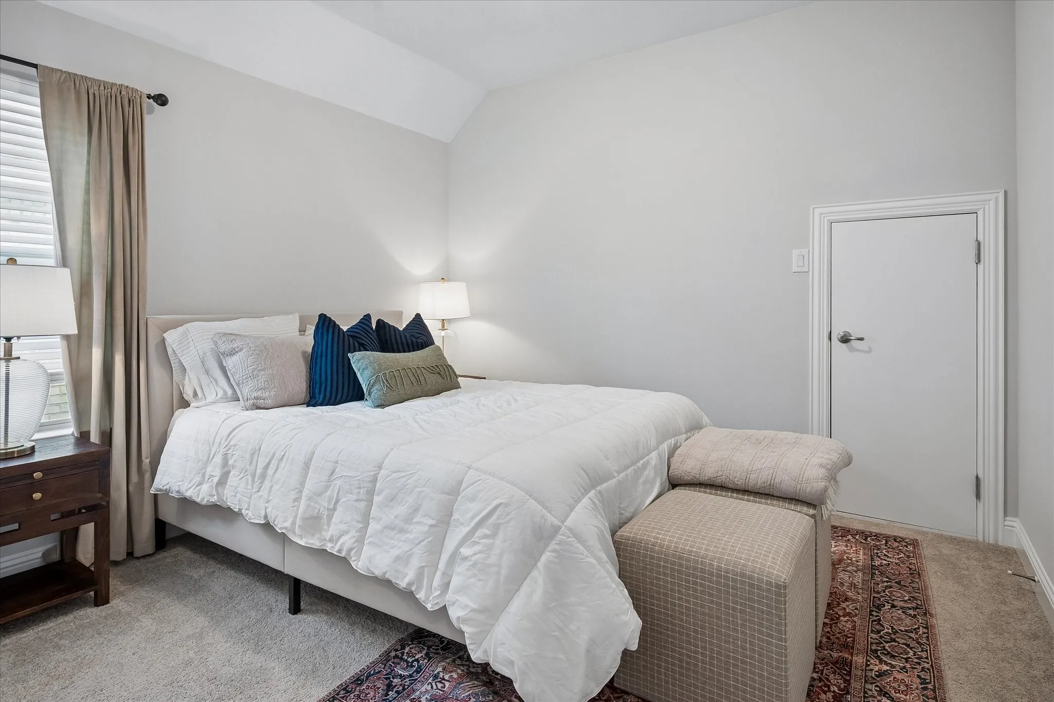 Upstairs third Bedroom featuring a Vaulted ceiling, carpeted flooring, and window with blinds.
