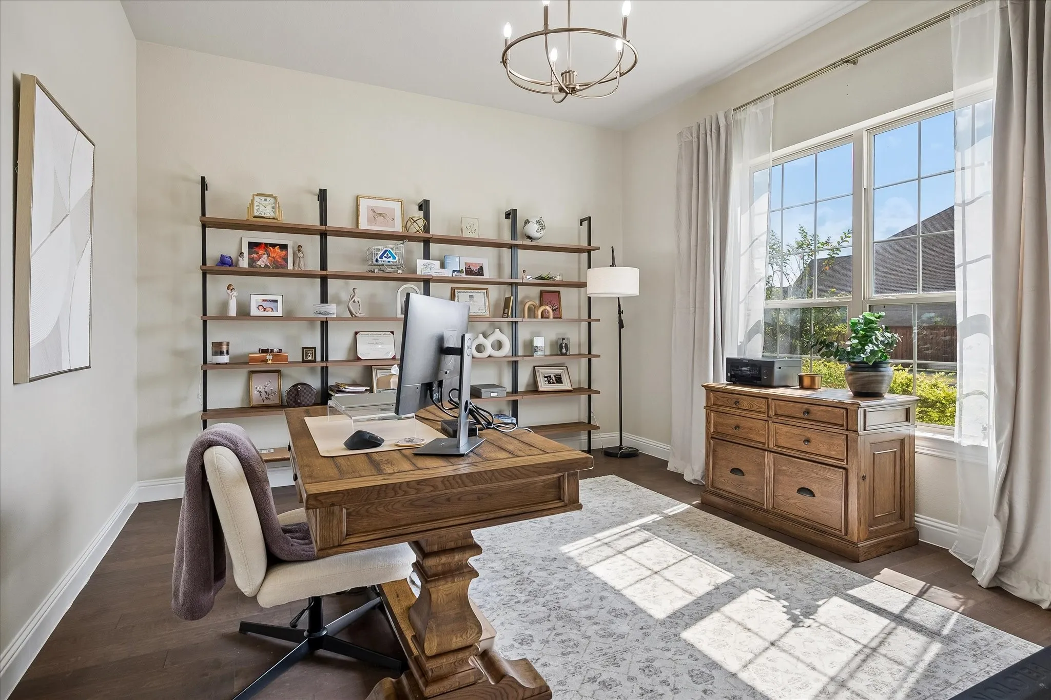 Sophisticated home office featuring wood flooring, large multi-pane windows with natural light, and a neutral color palette.