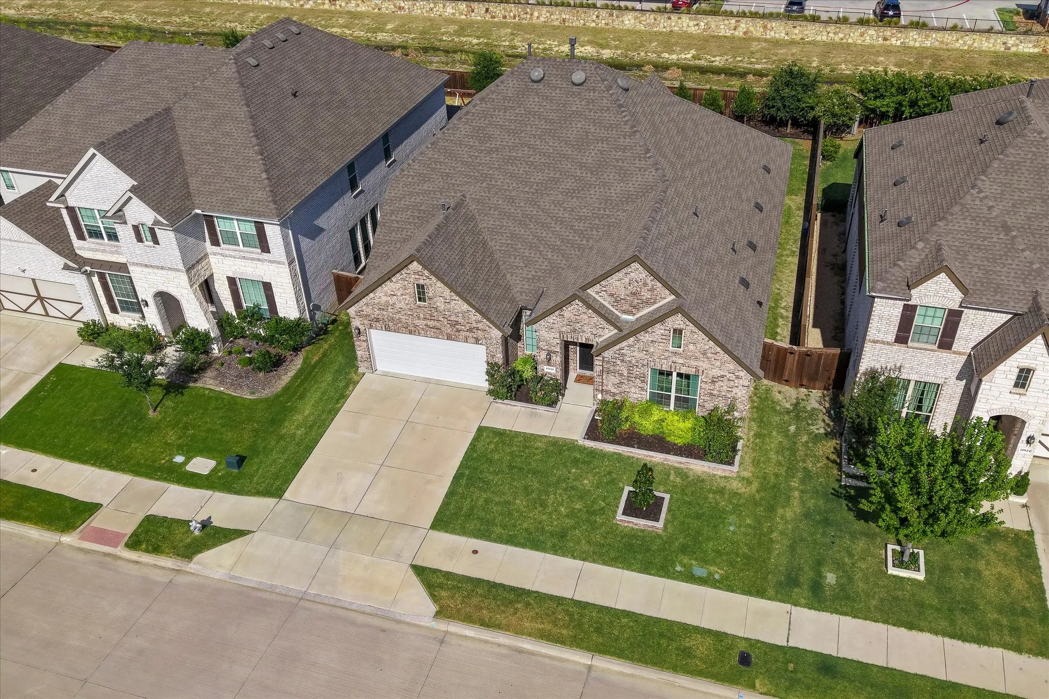 Brick exterior with attached two-car garage, concrete driveway, and front landscaping