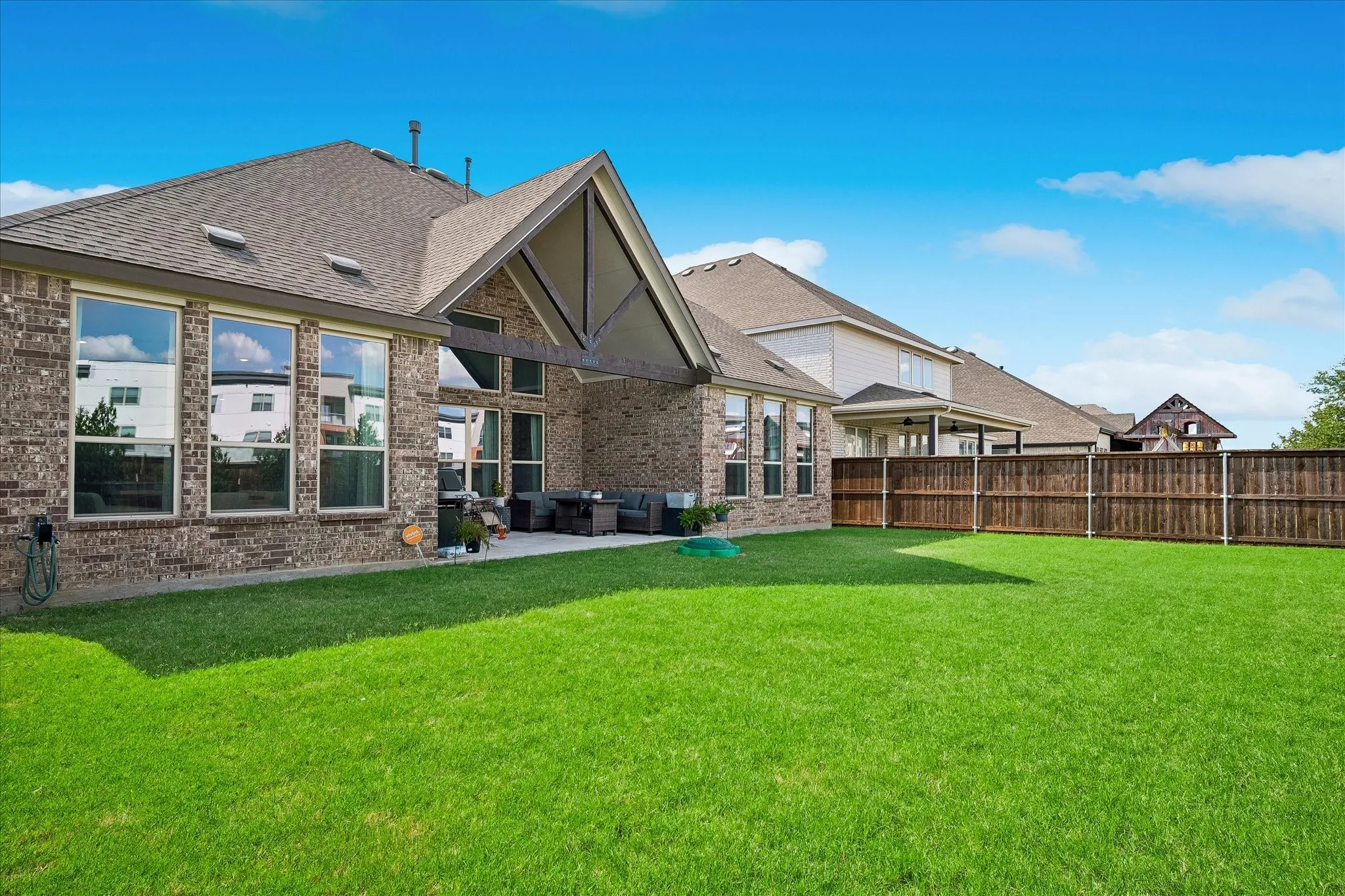 Expansive backyard featuring a manicured lawn, covered patio and wooden privacy fencing