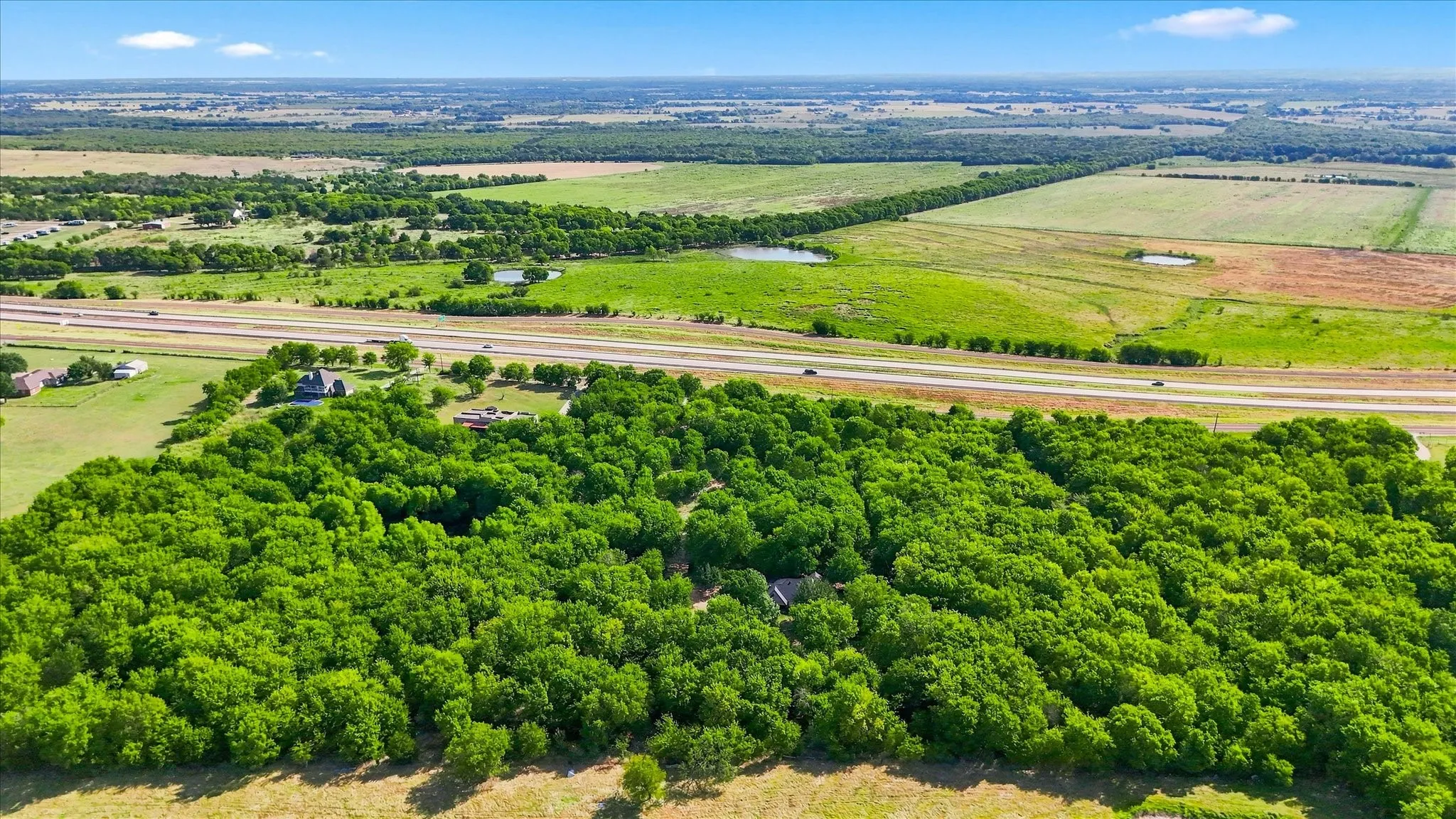 Expansive treed acreage with clearings, bordered by a multi-lane highway