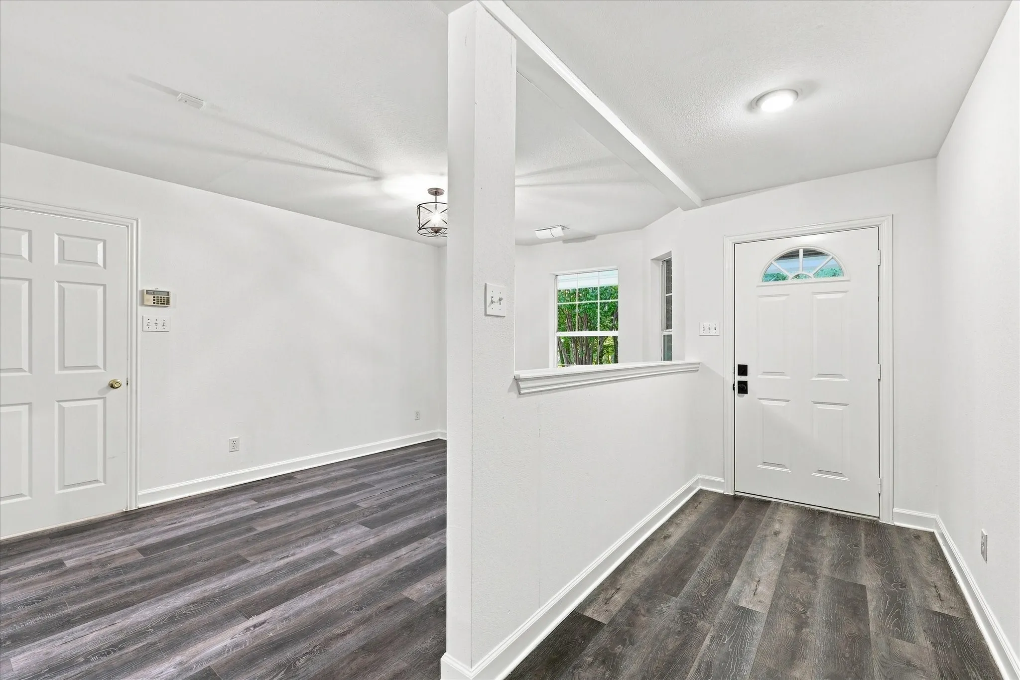 Wood-finish flooring, white paneled doors, recessed lighting, and a partial wall with cap molding