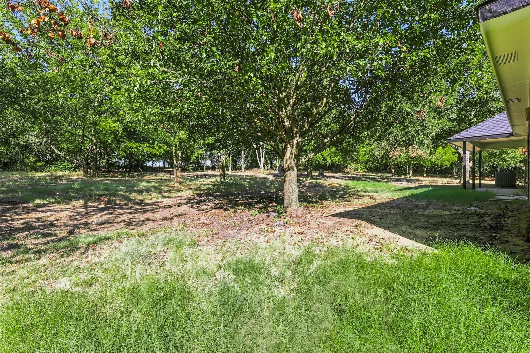 Mature shade trees and lush green lawn create a serene outdoor setting