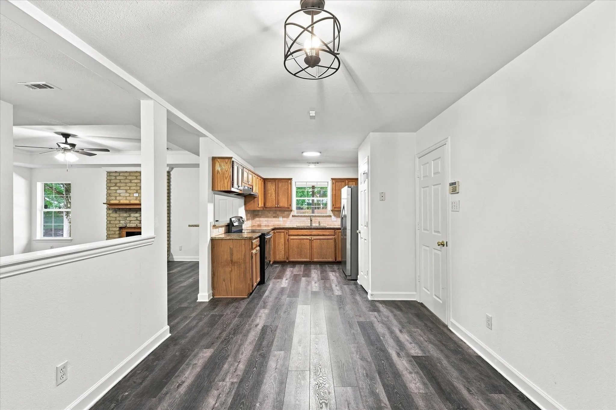 Wood-finish flooring, recessed lighting, and a kitchen featuring wood cabinetry, stainless steel appliances, and a tiled backsplash
