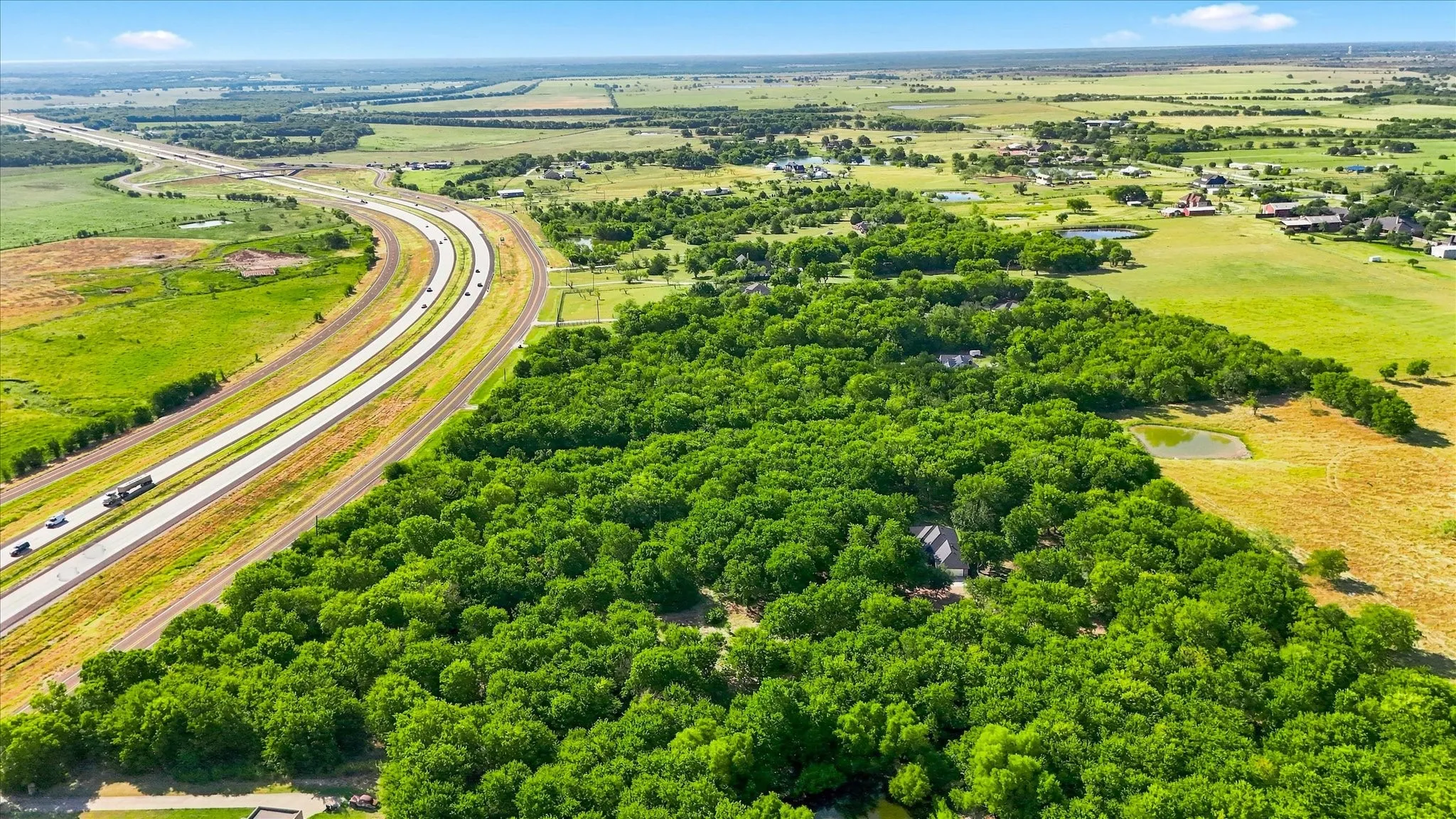 Expansive natural landscape with mature trees and a highway