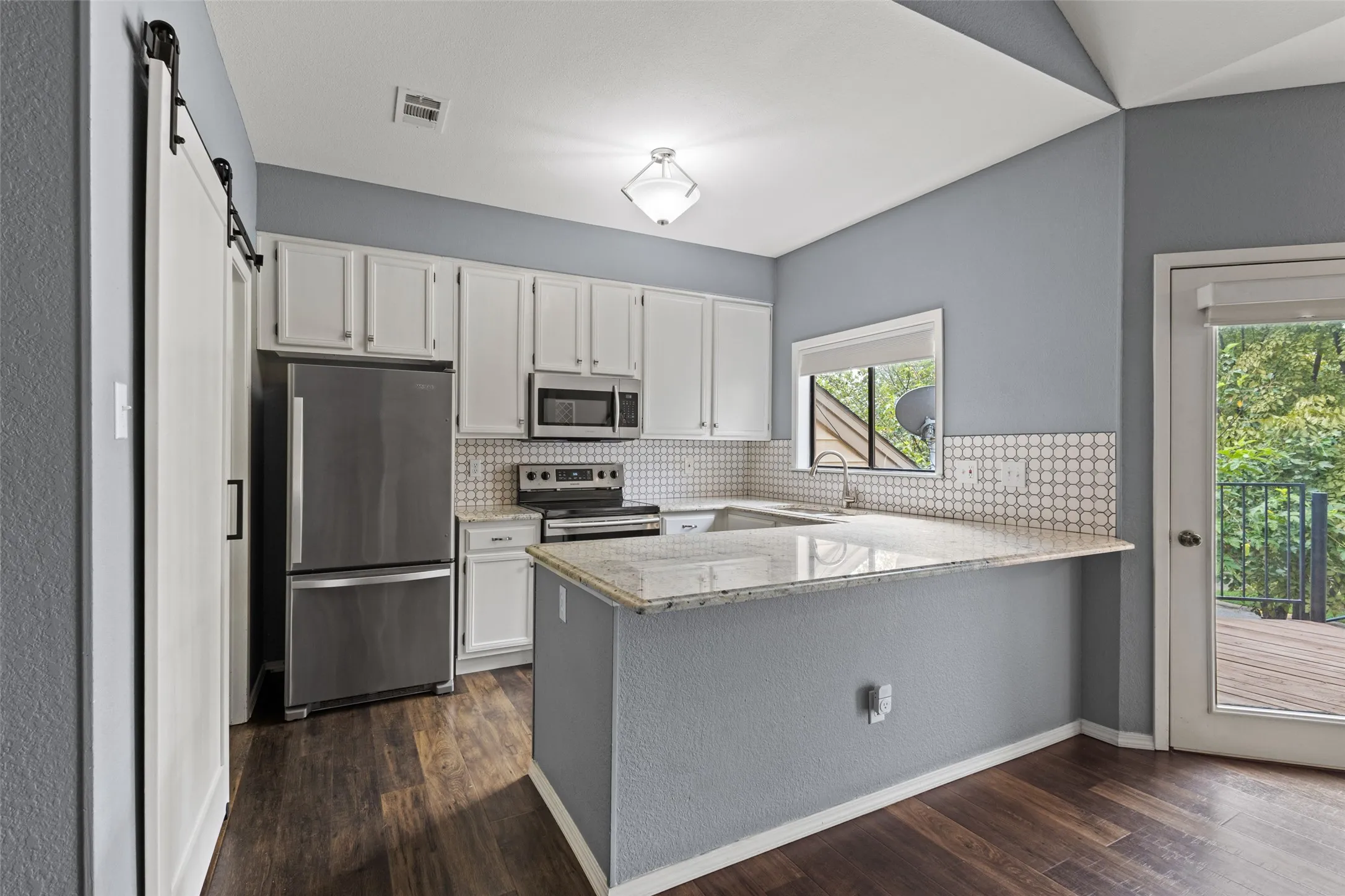 Kitchen featuring white cabinetry, wood-finish flooring, light-toned countertops, and a sliding barn door