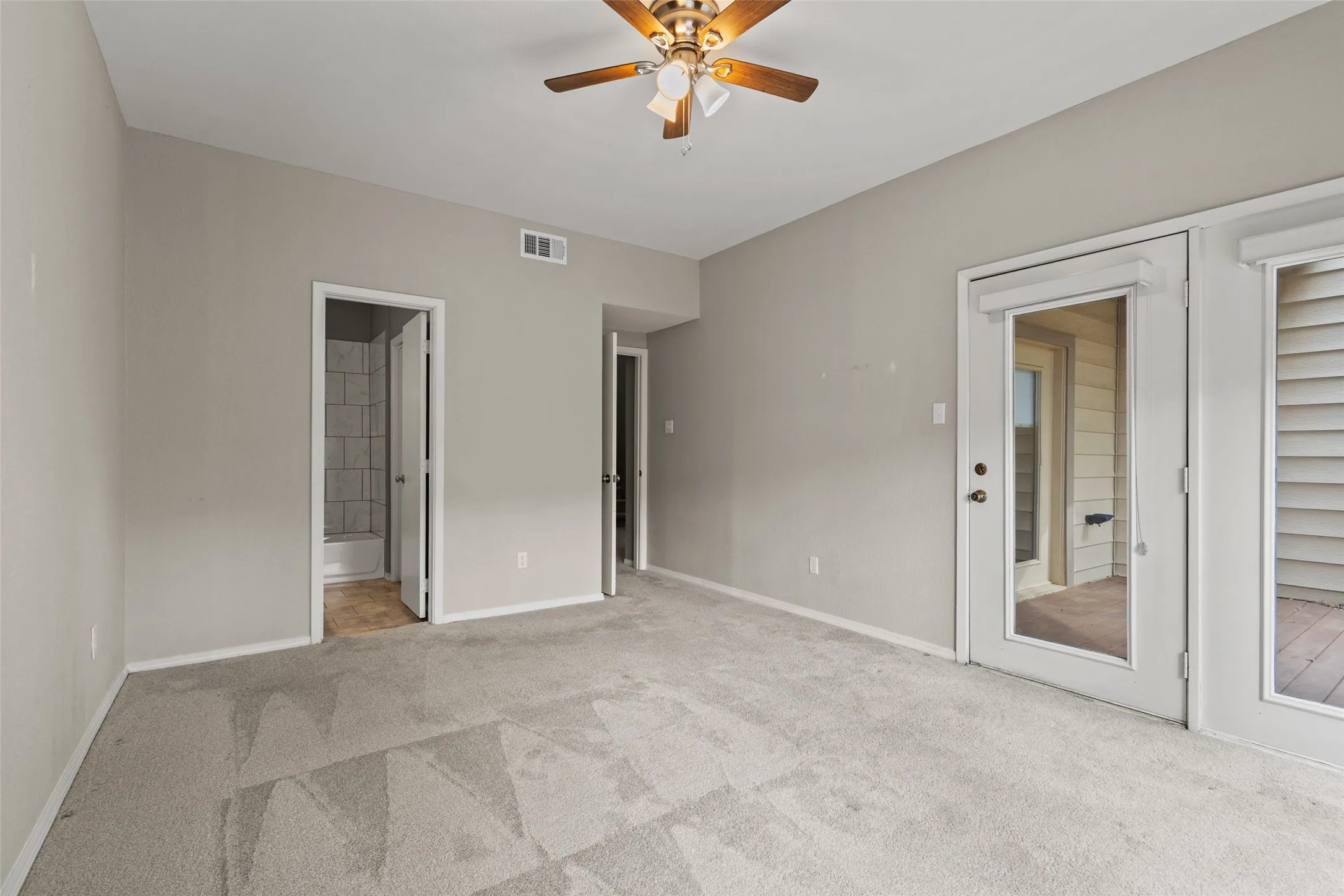Carpeted flooring, ceiling fan, and access to a balcony through French doors