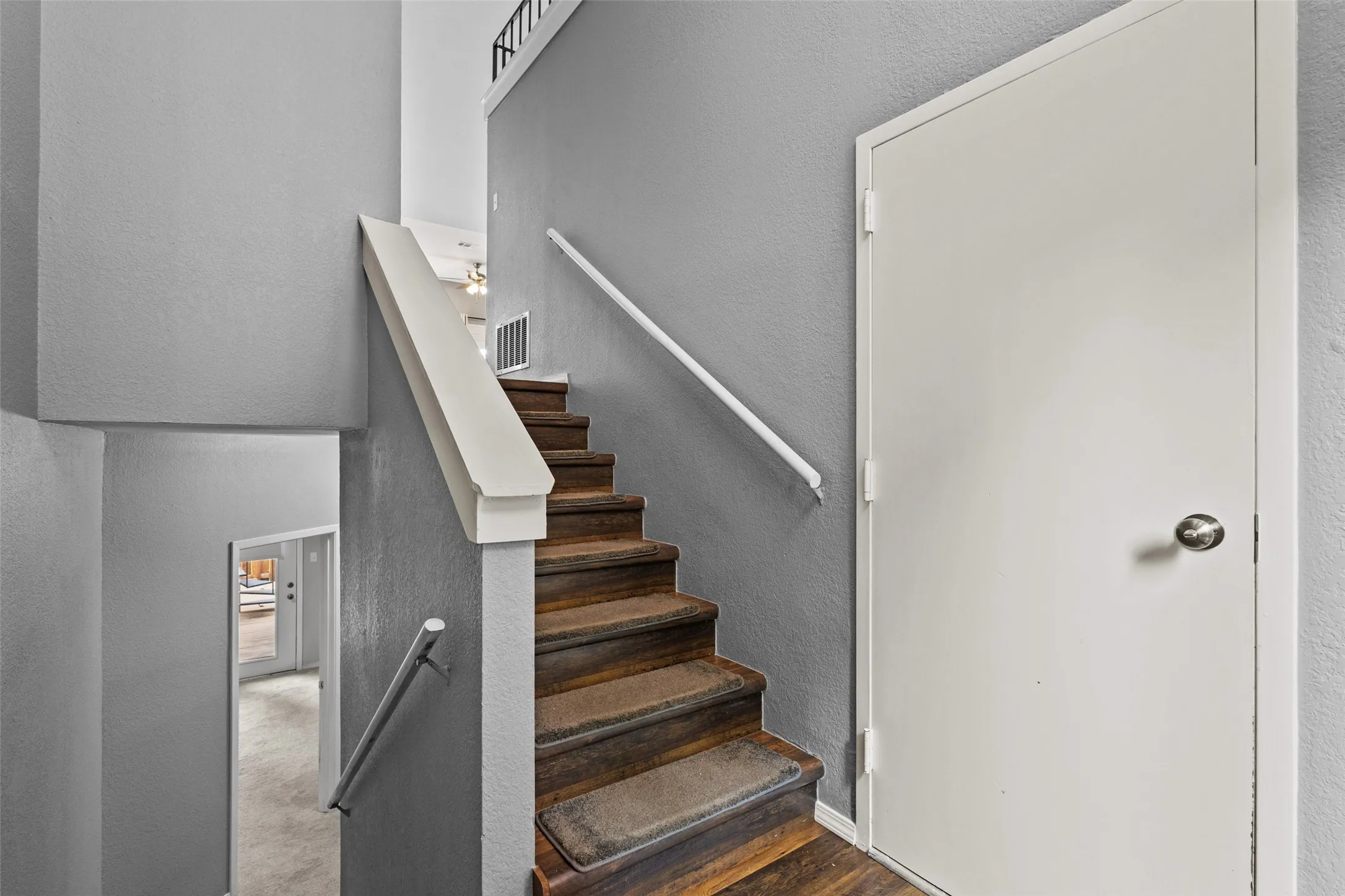 Wood-finish staircase with white risers and handrails