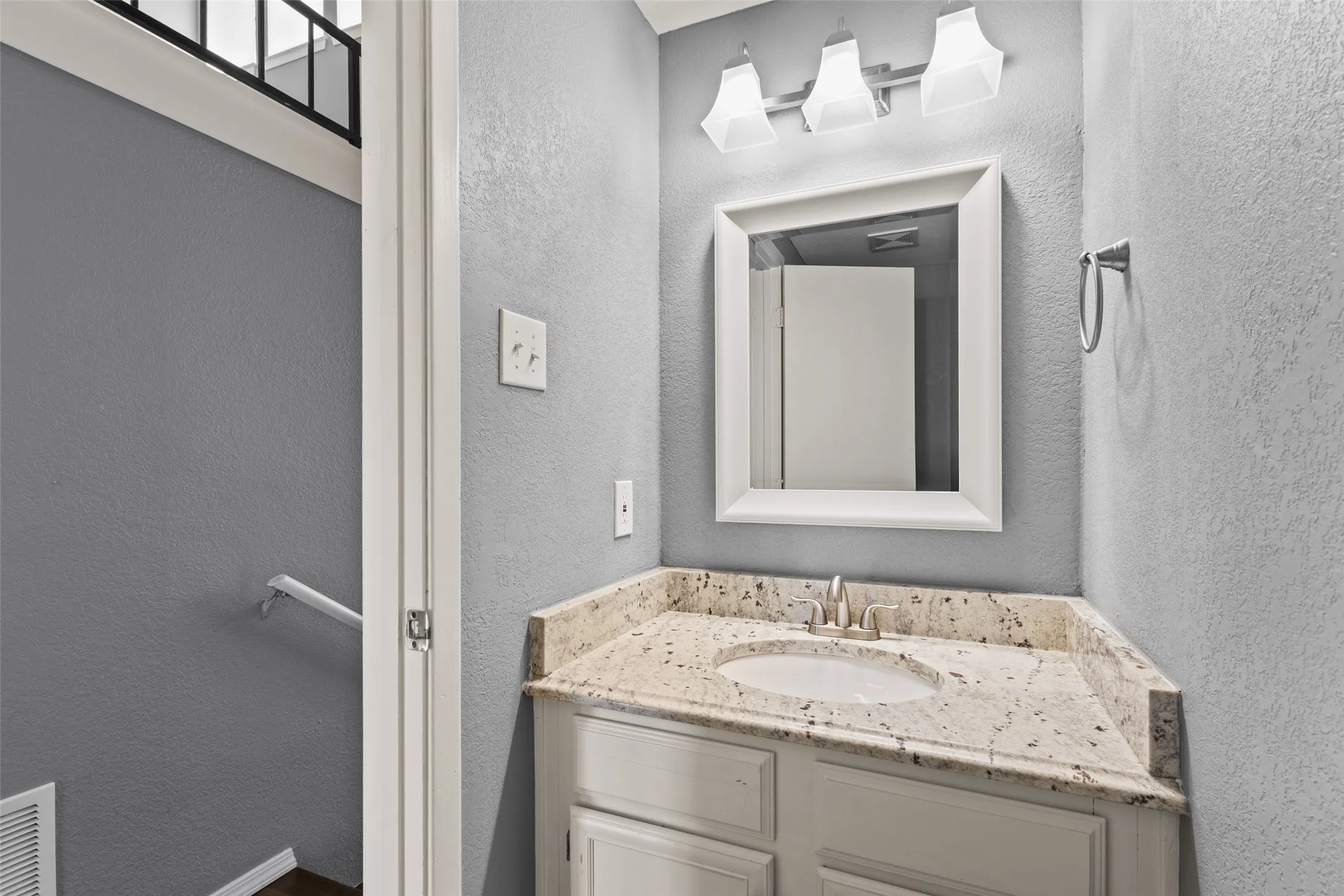 Vanity with a built-in sink, granite-style countertop, and white cabinetry