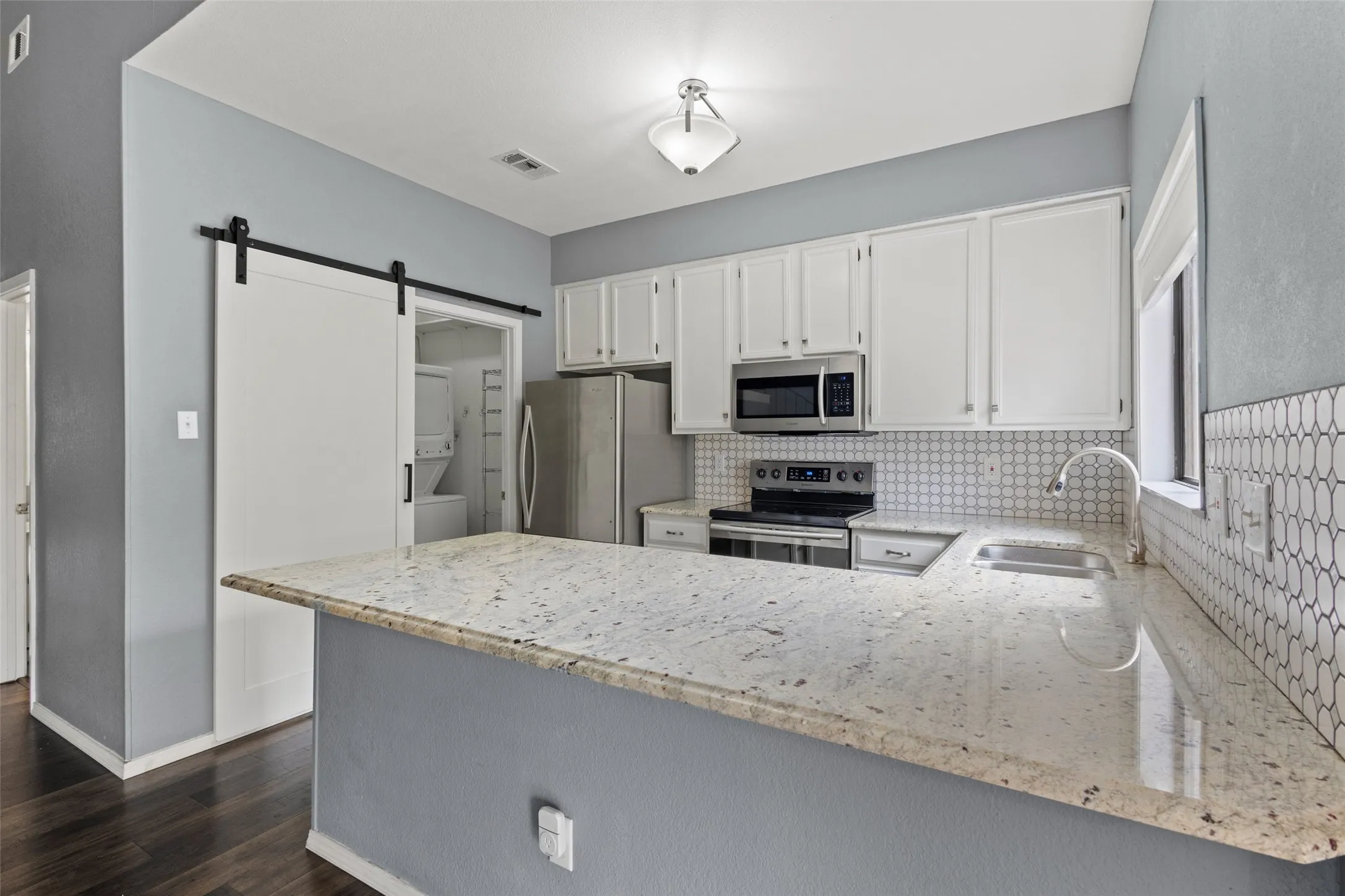 Kitchen featuring wood-finish flooring, white cabinetry, light-toned countertops, and a white penny tile backsplash