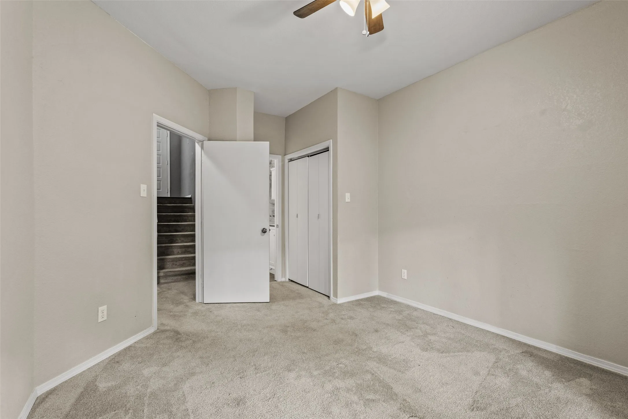Neutral painted walls, wall-to-wall carpeting, ceiling fan with integrated lighting, and bi-fold closet doors