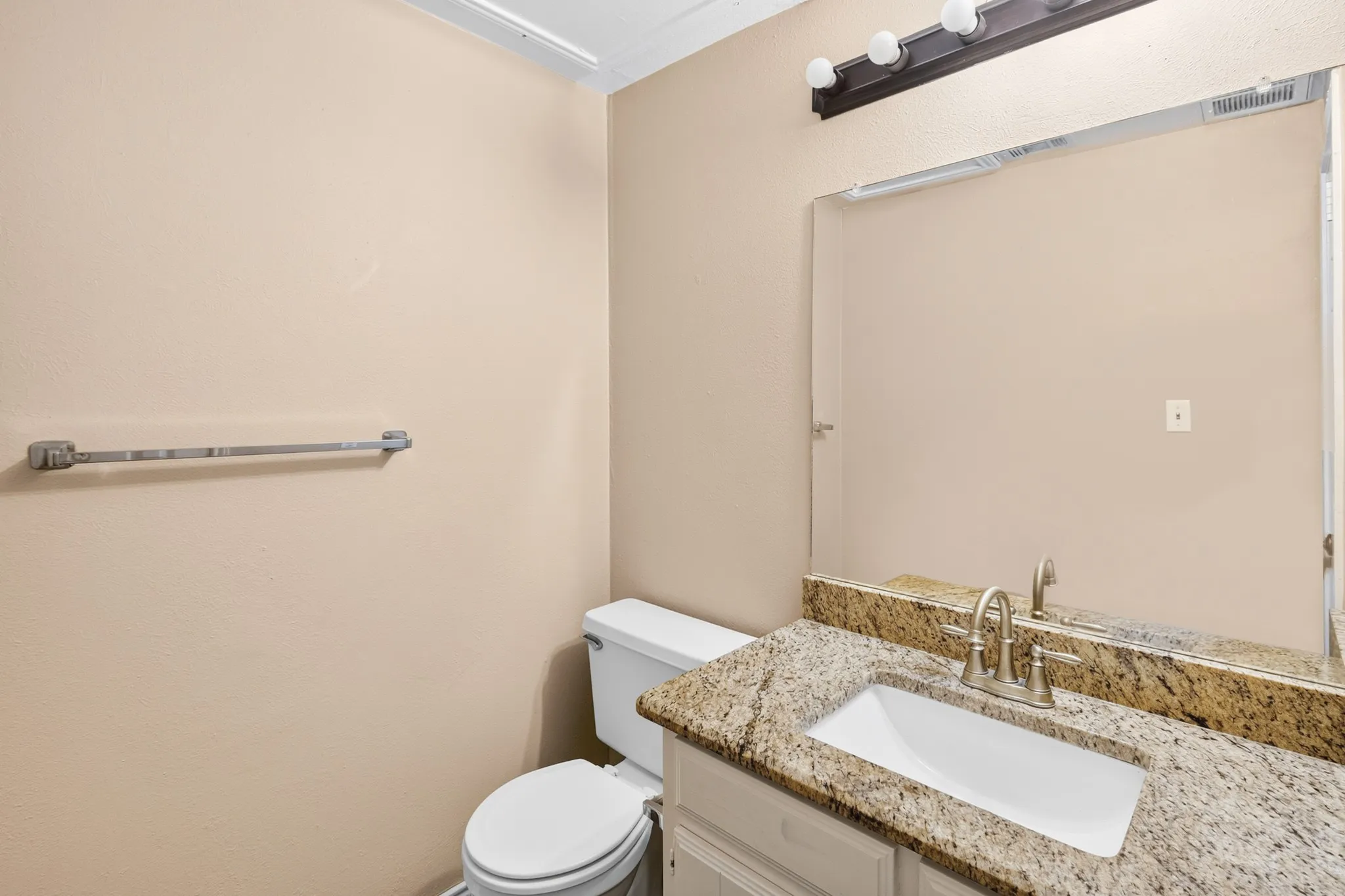 Granite-style countertop, undermount sink, brushed nickel faucet, large vanity mirror, and white vanity cabinetry