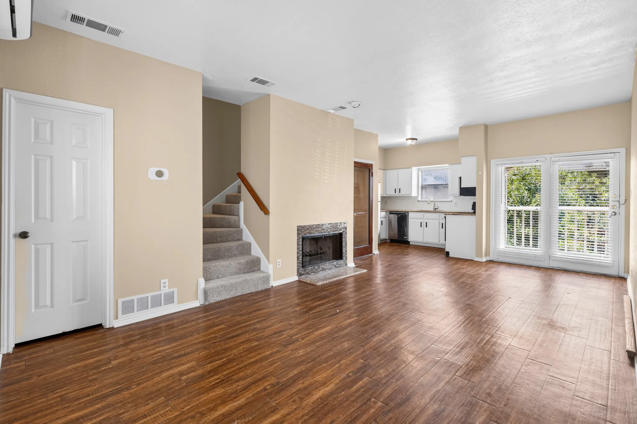 Wood-finish flooring throughout, with a stone-surround fireplace, and white kitchen cabinetry