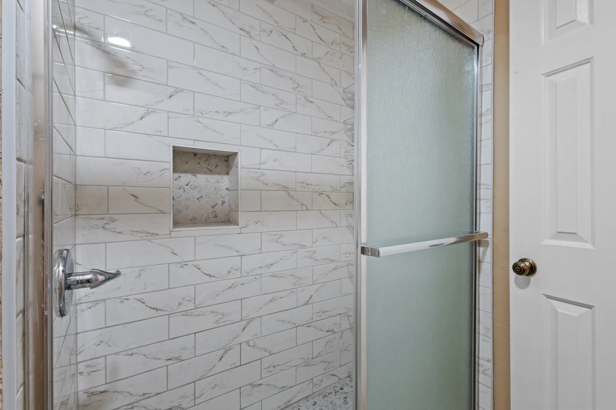 Shower enclosure with white subway tile, a built-in niche with mosaic tile, and a sliding glass door