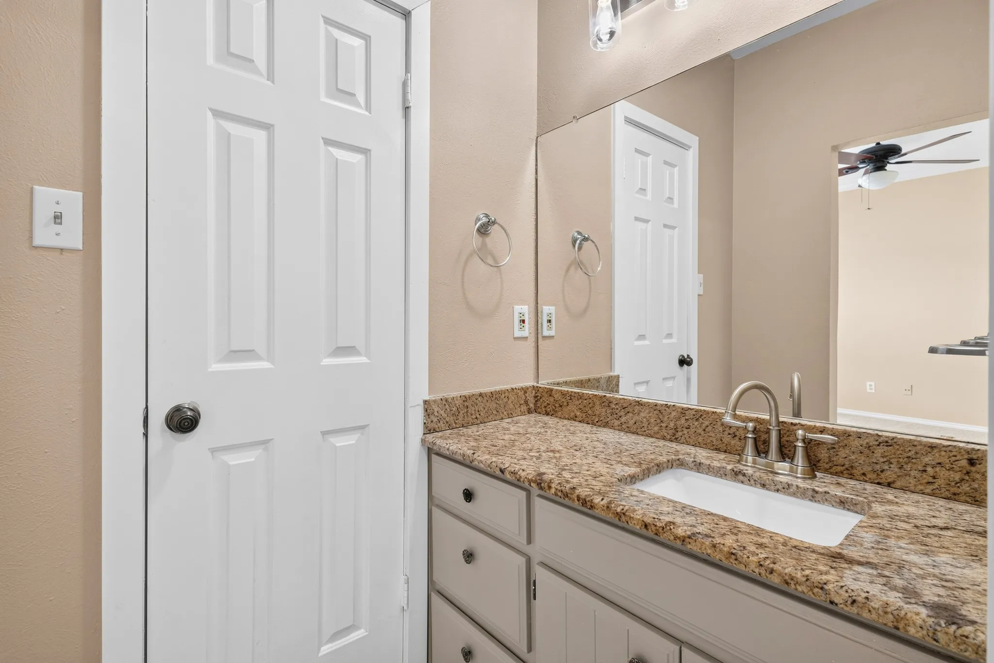 Vanity with granite countertop, integrated sink, and brushed nickel faucet