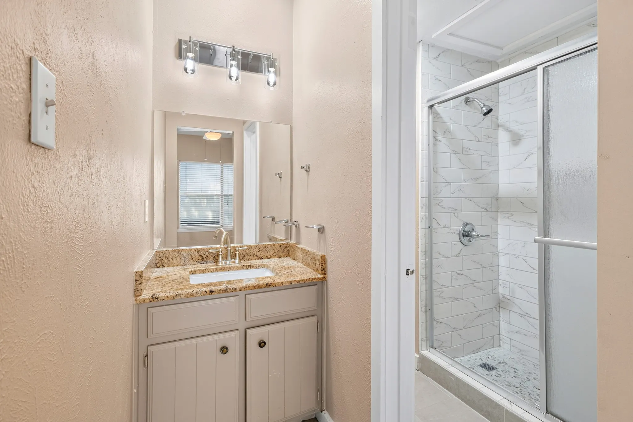 Vanity with granite countertop and undermount sink, brushed nickel faucet, and three-light fixture