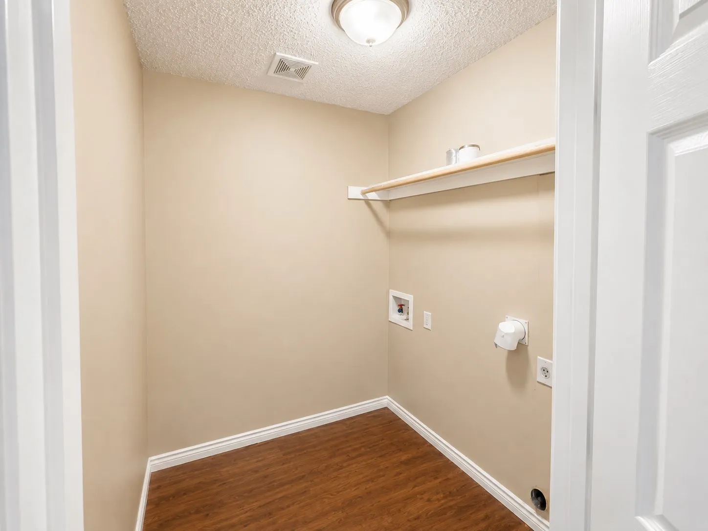 Laundry area featuring wood-finish flooring, a built-in shelf, and ceiling-mounted lighting