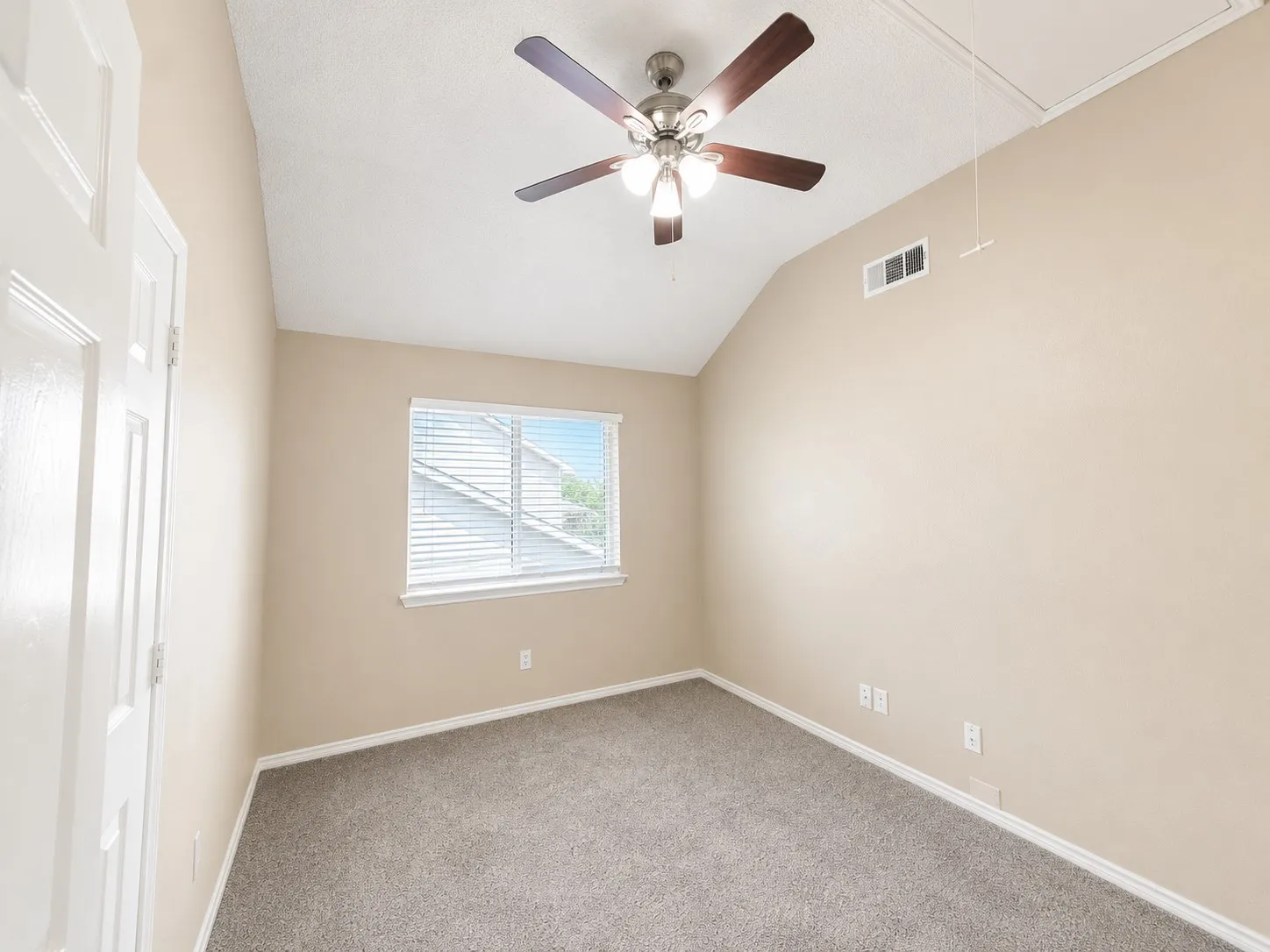 Neutral wall tones, vaulted ceiling, ceiling fan with integrated lighting, window with blinds, and gray carpet