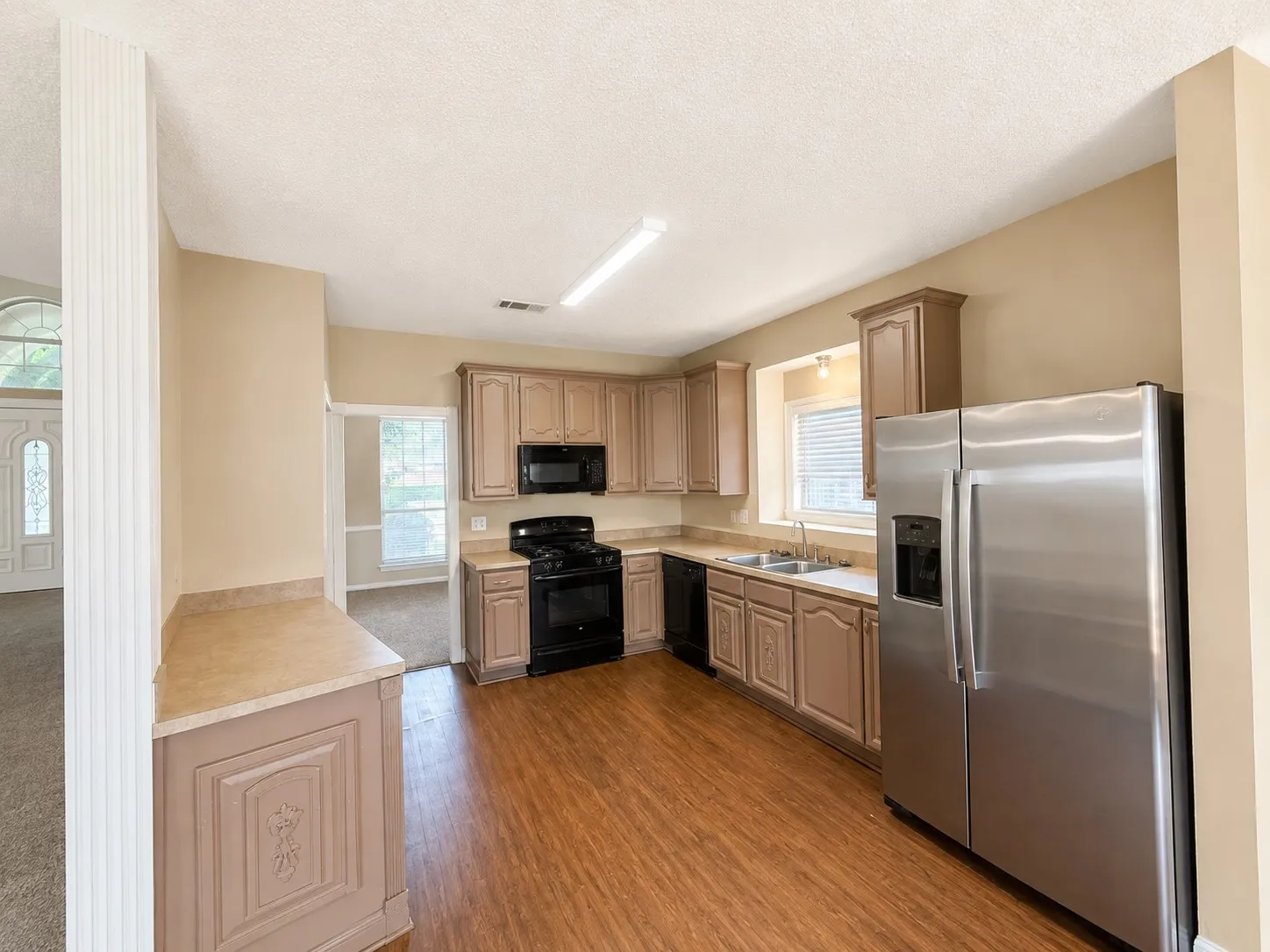 Kitchen with wood-finish flooring, stainless steel side-by-side refrigerator, black range, and built-in microwave