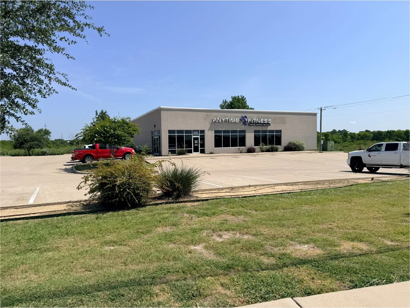 Commercial building with a stucco exterior, multiple large windows, and a paved parking lot