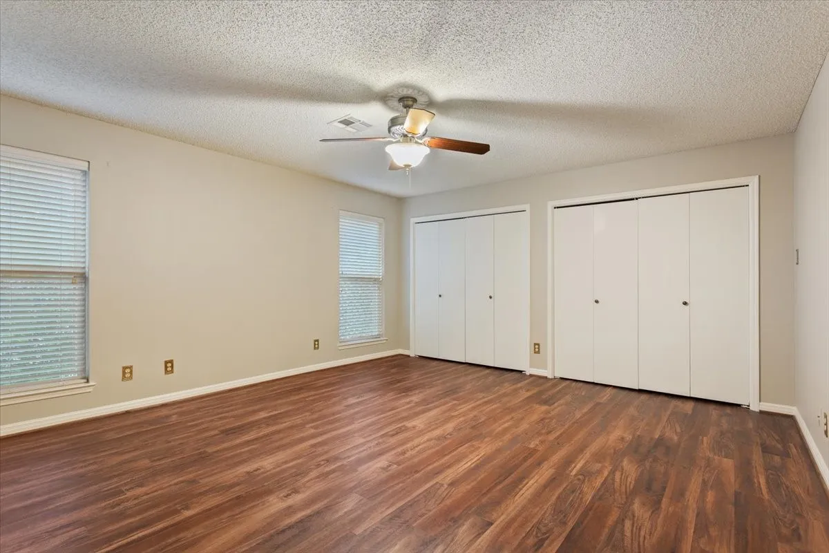Vinyl flooring, two windows with blinds, ceiling fan, and two sets of bi-fold closet doors