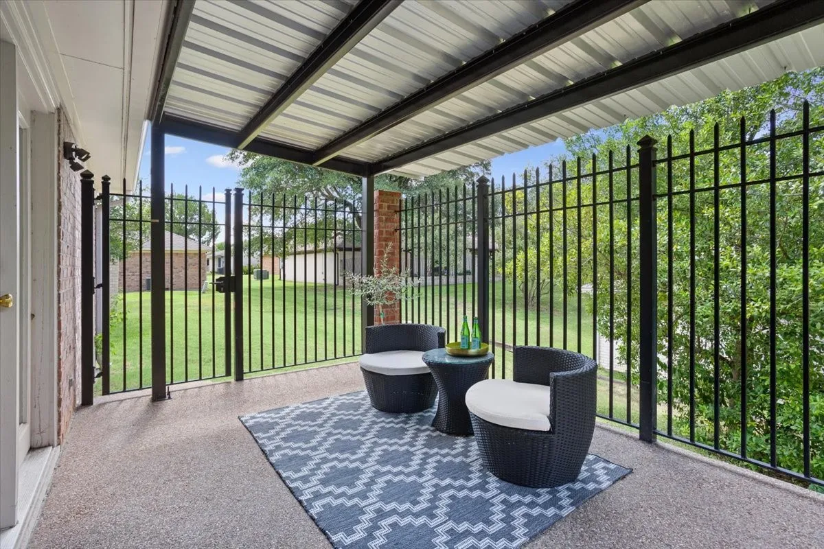 Covered back patio with a corrugated metal roof and black metal fencing