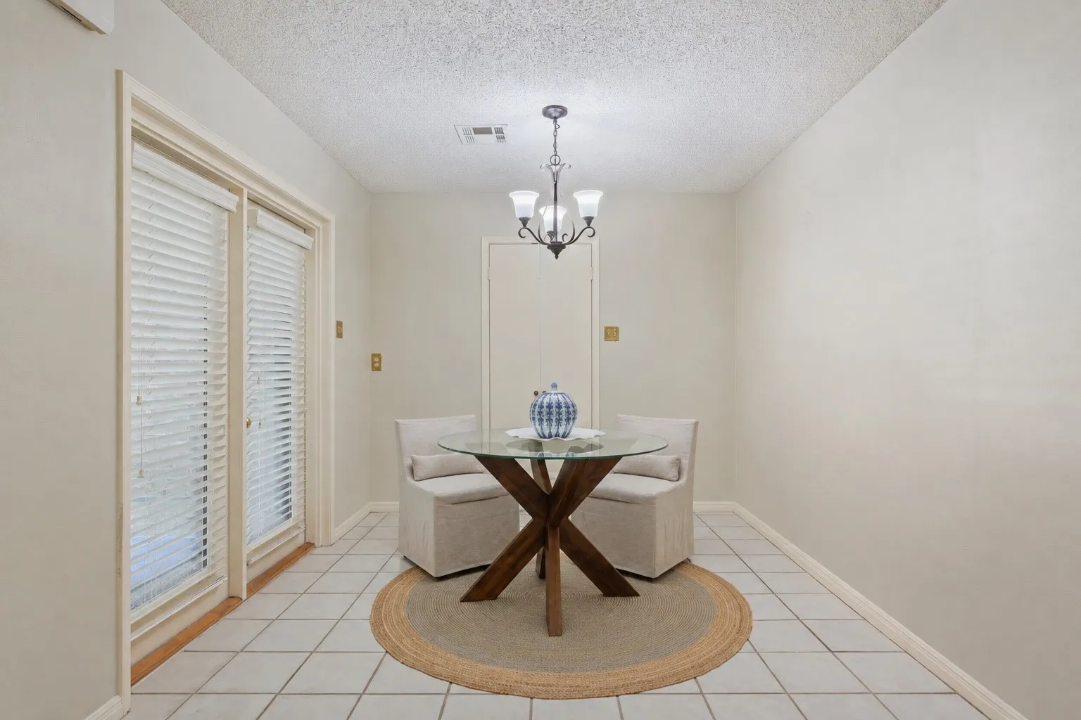 Recessed ceiling, tile flooring, glass-paned double doors, white wall finishes, and a dark bronze chandelier
