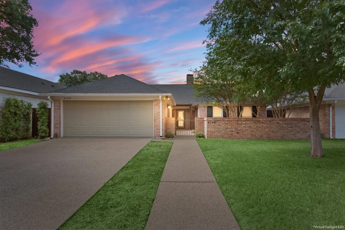 Brick exterior, attached two-car garage, concrete driveway, front lawn, and mature trees