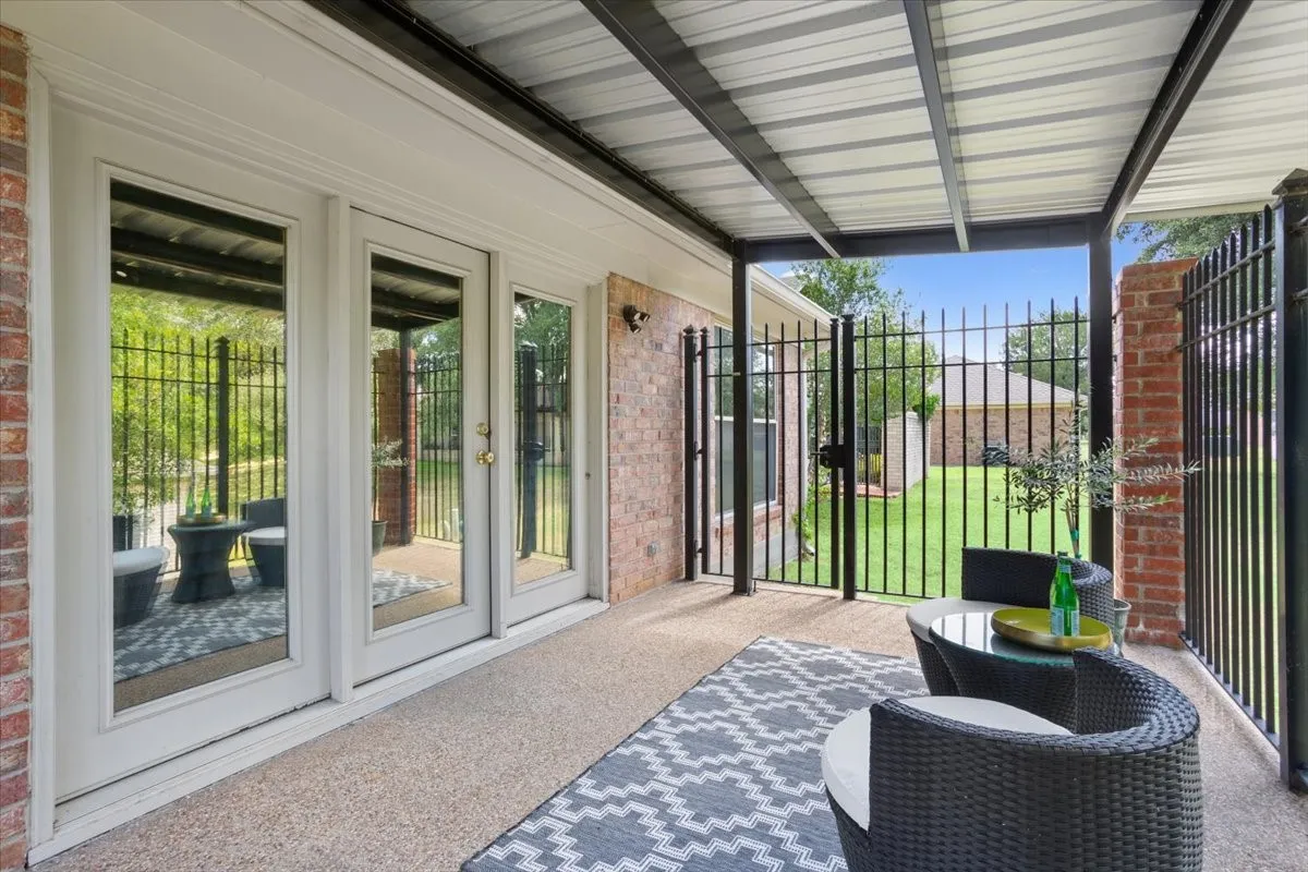 Covered back patio with a corrugated metal roof and black metal fencing
