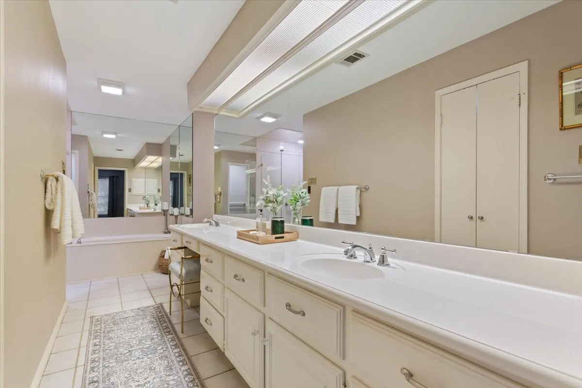 Spa-inspired primary bathroom featuring dual vanities with white cabinetry and polished chrome fixtures