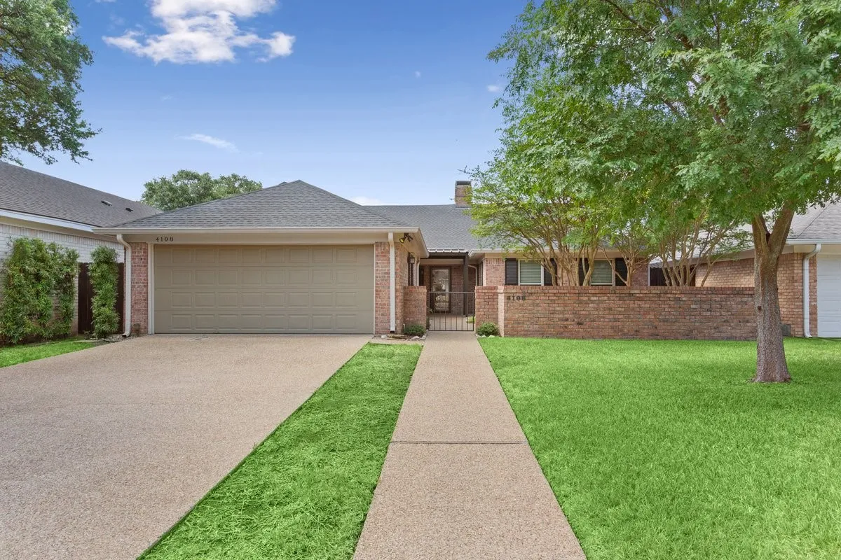 Brick exterior with a peaked roof, featuring an attached garage and a gated courtyard
